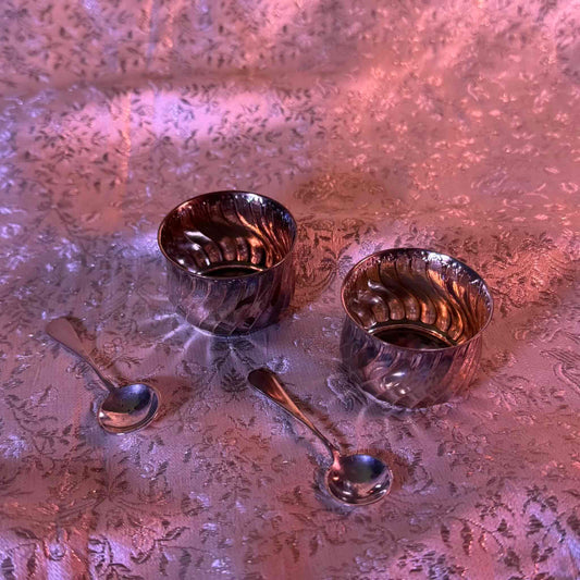 日本語: 優美なフランス製シルバー製ソルトセラー、サルロン(ソルト入れ、塩入れ)セット。貝殻をモチーフにしたデザインで、シルバー製スプーン2本付き。19世紀後期から20世紀初頭に製作。ミネルバ刻印入り。; English: Elegant French silver salt cellar (salière) set with shell-inspired design and matching silver spoons. Features Minerva hallmark. Late 19th to early 20th century. ; Français: Ensemble élégant de salières en argent français avec cuillères assorties, motif inspiré des coquillages. Poinçon Minerve. Fin du 19ᵉ siècle à début du 20ᵉ siècle.