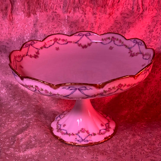 日本語: テオドール・アビランド製リモージュの磁器製フルーツスタンド。バラのガーランドとリボン装飾、金彩の縁取りが特徴。18世紀後期フランス様式を反映したデザイン。; English: Théodore Haviland Limoges porcelain fruit bowl with rose garlands, ribbon motifs, and gold trim. Inspired by late 18th-century French style. ; Français: Coupe à fruits en porcelaine Limoges de Théodore Haviland, décorée de guirlandes de roses, rubans et bordure dorée, dans le style français de la fin du 18ᵉ siècle.