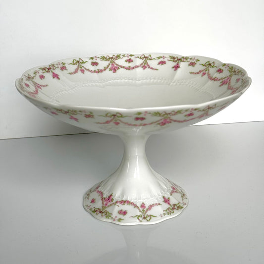 English: Ahrenfeldt Limoges porcelain compote on pedestal with ribbon and floral garland decoration, late 19th to early 20th century, France. ;
Français : Compotier en porcelaine de Limoges Ahrenfeldt sur piédouche, décor de rubans et guirlandes de fleurs, fin XIXᵉ – début XXᵉ siècle. ;
日本語: アーレンフェルト製 リモージュ磁器の脚付きコンポティエ(フルーツスタンド)。リボンとガーランドの装飾、19世紀末〜20世紀初頭 フランス。