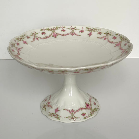English: Ahrenfeldt Limoges porcelain compote on pedestal with ribbon and floral garland decoration, late 19th to early 20th century, France. ;
Français : Compotier en porcelaine de Limoges Ahrenfeldt sur piédouche, décor de rubans et guirlandes de fleurs, fin XIXᵉ – début XXᵉ siècle. ;
日本語: アーレンフェルト製 リモージュ磁器の脚付きコンポティエ(フルーツスタンド)。リボンとガーランドの装飾、19世紀末〜20世紀初頭 フランス。