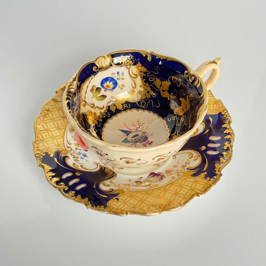 Antique English porcelain teacup and saucer, hand-painted floral and shell decor with heavy gold gilding.