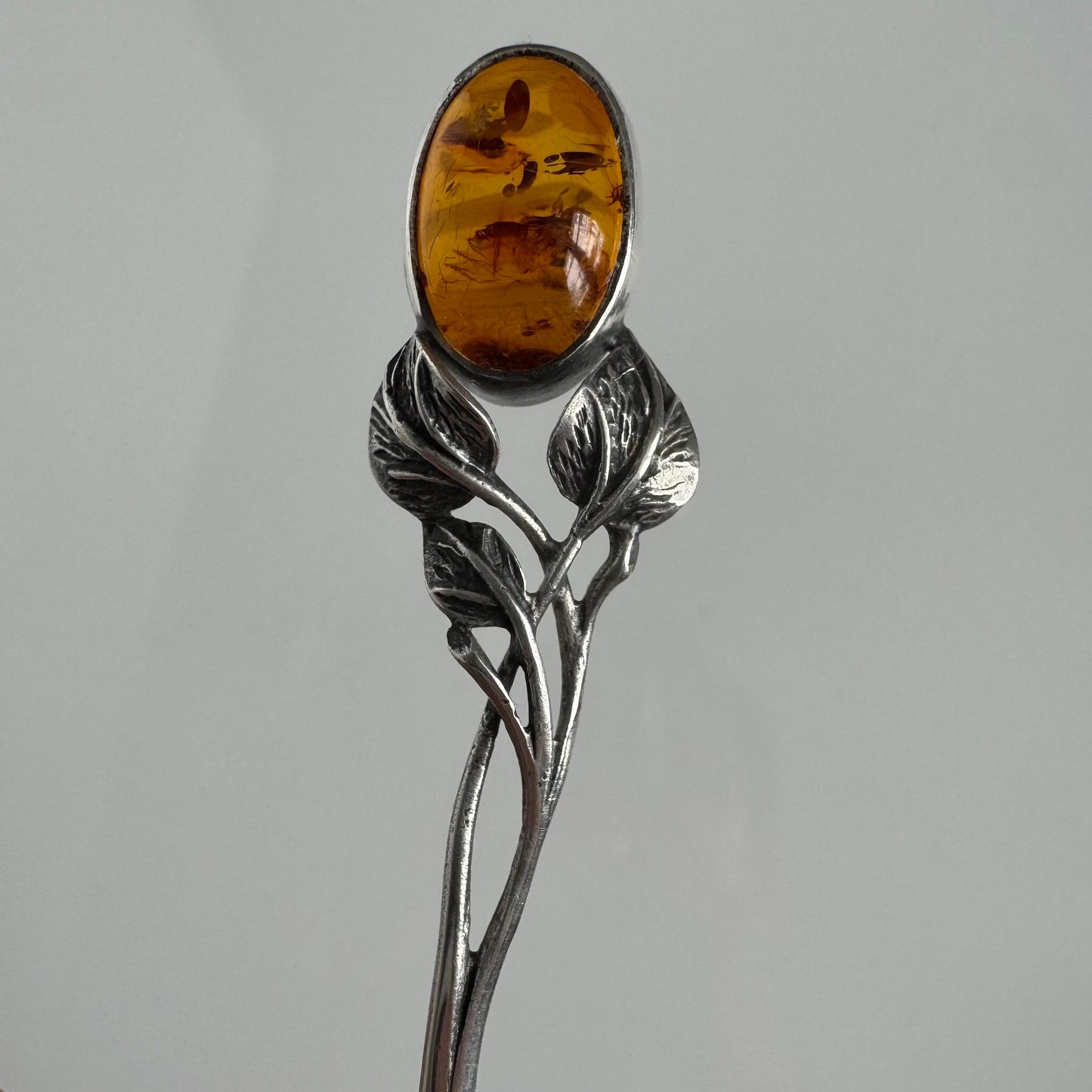 English: Art Nouveau style silver spoon with amber accent and delicate leaf motif, in 925 silver ; 日本語: アンバー(琥珀)付きアール・ヌーヴォー様式のシルバースプーン、繊細な葉モチーフと925シルバーの装飾 ; Français: Cuillère en argent style Art Nouveau avec ambre, décorée d’un motif feuillage délicat en argent 925.