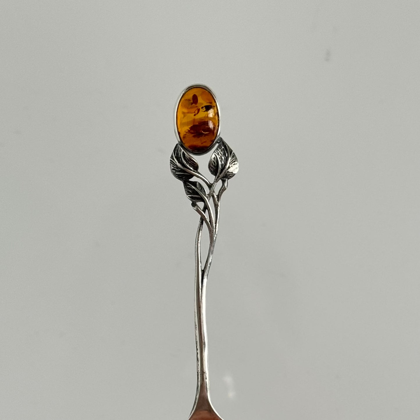 English: Art Nouveau style silver spoon with amber accent and delicate leaf motif, in 925 silver ; 日本語: アンバー(琥珀)付きアール・ヌーヴォー様式のシルバースプーン、繊細な葉モチーフと925シルバーの装飾 ; Français: Cuillère en argent style Art Nouveau avec ambre, décorée d’un motif feuillage délicat en argent 925.