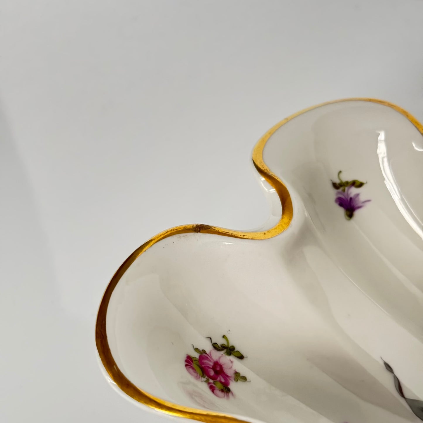 English: Herend porcelain shell-shaped dish with hand-painted floral design and gold accents, vintage home decor piece; 日本語: ヘレンド製貝殻型ポーセリンプレート、ハンドペイントの花柄と金彩装飾が施されたヴィンテージインテリア; Français: Plat en porcelaine Herend en forme de coquillage, décor floral peint à la main avec des accents dorés, objet de décoration vintage.