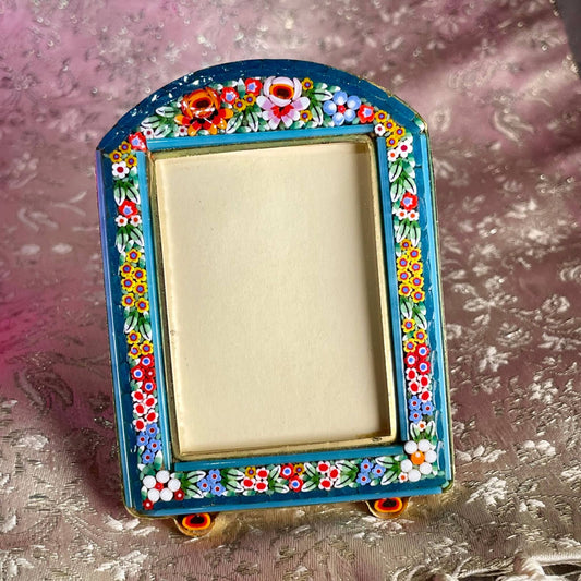 日本語: イタリア製のミクロモザイクフォトフレーム。鮮やかな花柄が特徴で、活気と可愛らしさを演出します。特別な瞬間を飾りながら、エレガントなアクセントを加えるアイテムです。; English: Italian-made micro-mosaic photo frame featuring a vibrant floral pattern, adding charm and elegance to your decor. A beautiful way to display special moments. ; Français: Cadre photo en micro-mosaïque fabriqué en Italie avec un motif floral vibrant, apportant charme et élégance à votre décoration. Une belle façon d'afficher des moments spéciaux.