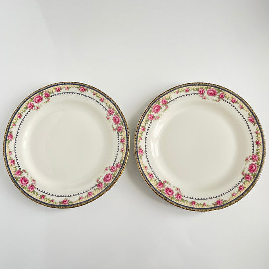 Pair of antique French Limoges porcelain dessert plates, 20th century. Delicate pink rose pattern on the rim, classic and elegant design.