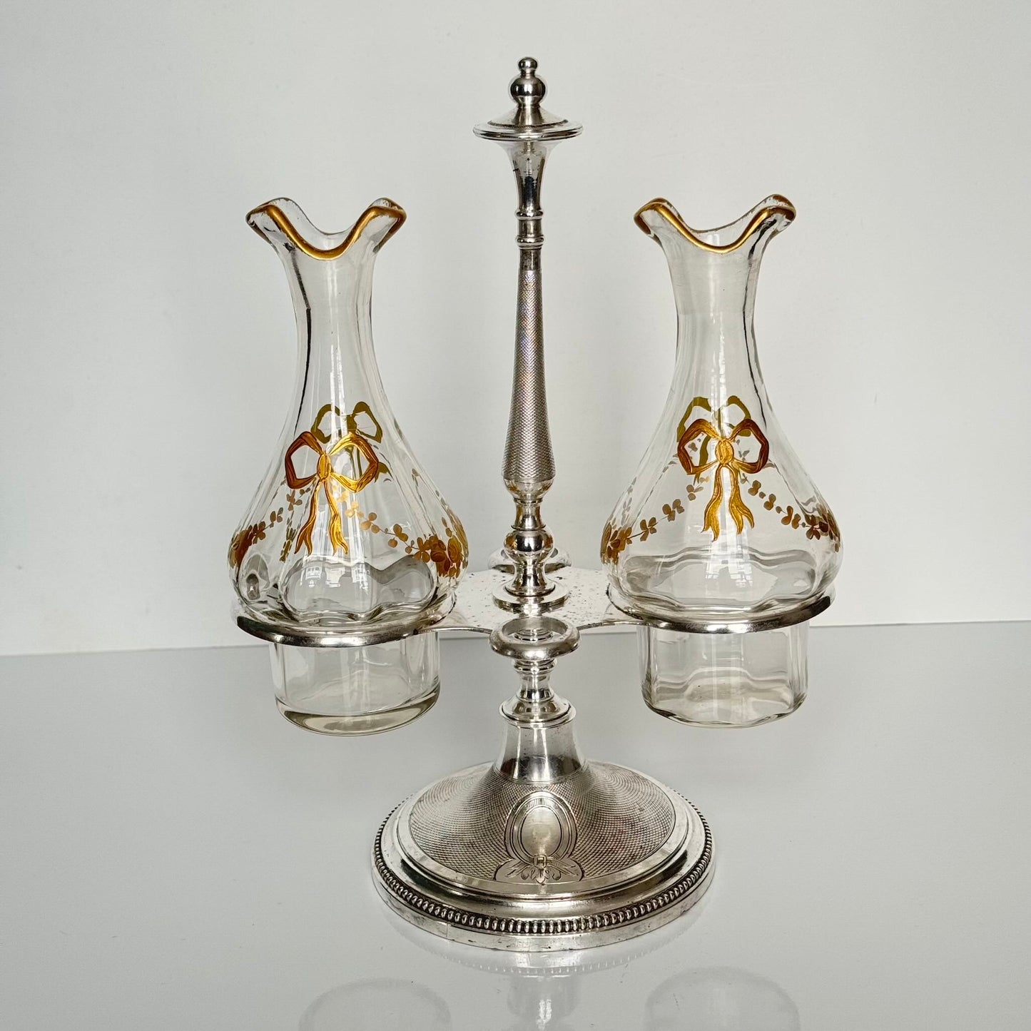 English: Silver plate cruet set by Armand Frénais, late 19th to early 20th century, with crystal bottles decorated with gilt ribbons and floral motifs; some wear and deformation to metal parts. ; 日本語: 19世紀末〜20世紀初頭、アルマン・フレネ製の銀メッキ製オイル&ビネガー入れセット。金彩リボンと花模様が施されたクリスタルボトル付き。金属部分にやや摩耗と歪みあり。; Français: Huilier vinaigrier en métal argenté par Armand Frénais, fin XIXe – début XXe siècle, flacons en cristal décorés de rubans et fleurs dorés ; quelques usures et déformations visibles sur le métal.