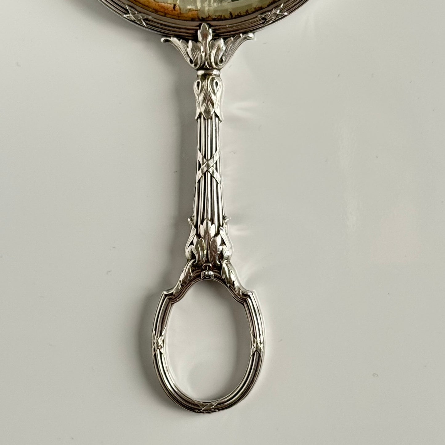 English: Silver plate hand mirror in Louis XVI style with crossed ribbons and decorative bow, late 19th to early 20th century, double-sided mirror ; 日本語: ルイ16世様式の銀メッキ手鏡、リボンと装飾的な結び目付き、19世紀末~20世紀初頭、両面鏡 ; Français: Miroir à main en métal argenté style Louis XVI avec rubans croisés et nœud, fin XIXe – début XXe siècle, miroir double face.