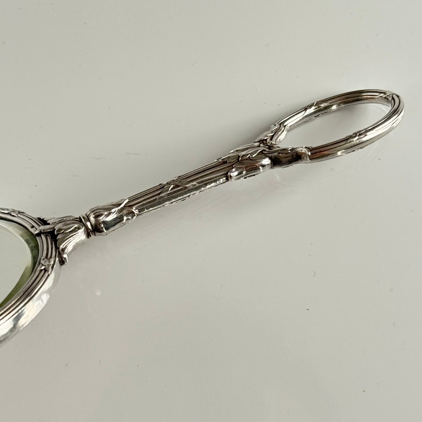 English: Silver plate hand mirror in Louis XVI style with crossed ribbons and decorative bow, late 19th to early 20th century, double-sided mirror ; 日本語: ルイ16世様式の銀メッキ手鏡、リボンと装飾的な結び目付き、19世紀末~20世紀初頭、両面鏡 ; Français: Miroir à main en métal argenté style Louis XVI avec rubans croisés et nœud, fin XIXe – début XXe siècle, miroir double face.
