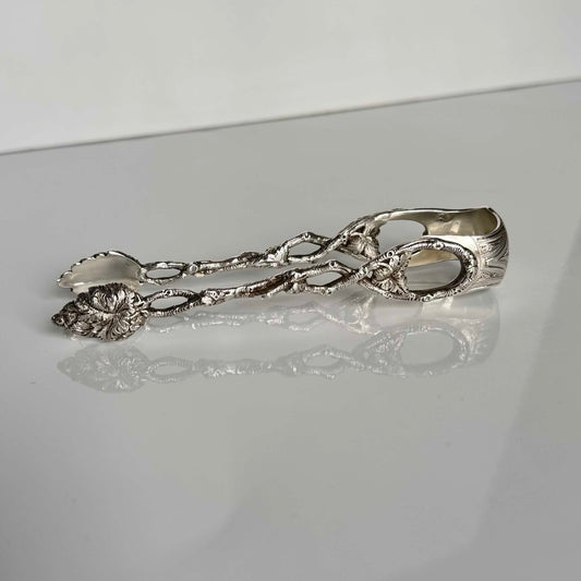English: Antique solid silver sugar tongs with branch and foliage motif, late 19th – early 20th century. Elegant craftsmanship with fine detailing. ; 日本語: 19世紀後期 – 20世紀初期のアンティーク純銀シュガートング。枝と葉のモチーフが施された精巧なデザイン。 ; Français: Pince à sucre ancienne en argent massif avec motif de branche et feuillage, fin XIXᵉ – début XXᵉ siècle. Travail d’orfèvrerie raffiné avec de superbes détails.