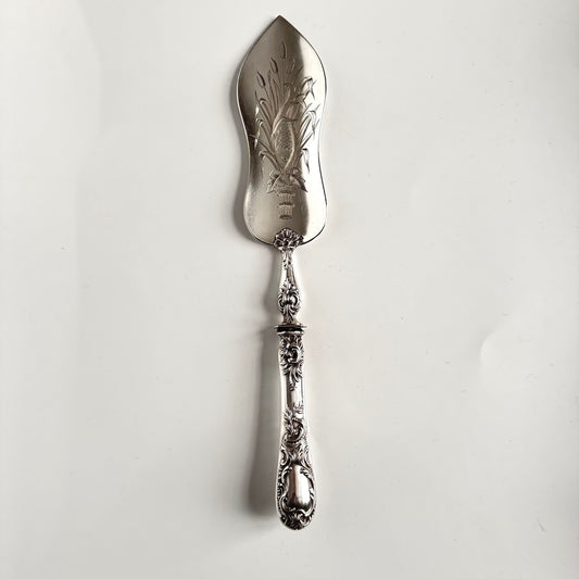 English: Solid silver fish server with Rocaille handle and finely chased fish and floral motifs, late 19th – early 20th century. Elegant craftsmanship with French silver hallmark. ; 日本語: 19世紀後期 - 20世紀初期の純銀製フィッシュサーバー。ロカイユ装飾のハンドルと精緻な魚と花の彫金が特徴。フランスの銀刻印付き。 ; Français: Pelle à poisson en argent massif avec manche Rocaille et décor ciselé de poisson et motifs floraux, fin 19ᵉ – début 20ᵉ siècle. Travail raffiné avec poinçon français.