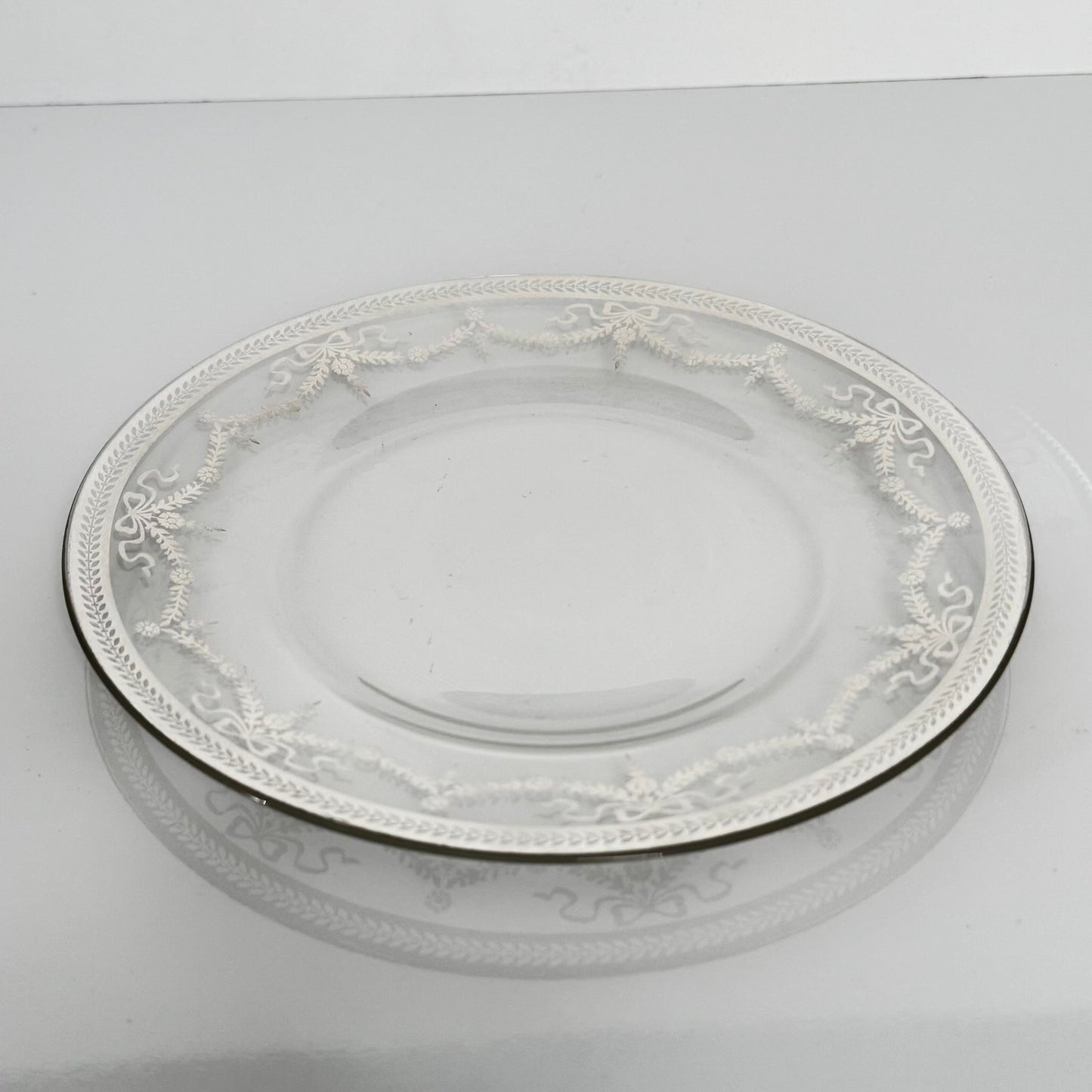 English: Vintage glass dessert plate with silvered ribbon and garland design, elegant and lightly worn. ; Français : Assiette à dessert en verre vintage avec décor argenté de rubans et guirlandes, élégante et en très bon état. ; 日本語: 銀彩のリボンとガーランド模様が施されたヴィンテージのガラス製デザートプレート。上品な印象でコンディション良好。