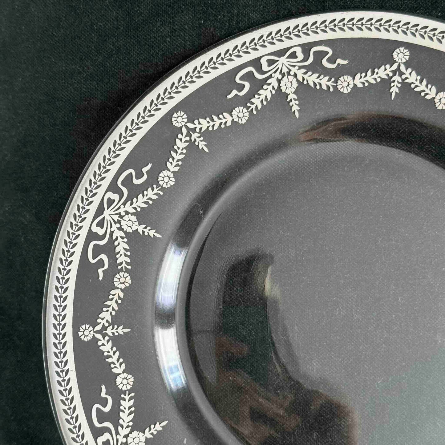 English: Vintage glass dessert plate with silvered ribbon and garland design, elegant and lightly worn. ; Français : Assiette à dessert en verre vintage avec décor argenté de rubans et guirlandes, élégante et en très bon état. ; 日本語: 銀彩のリボンとガーランド模様が施されたヴィンテージのガラス製デザートプレート。上品な印象でコンディション良好。