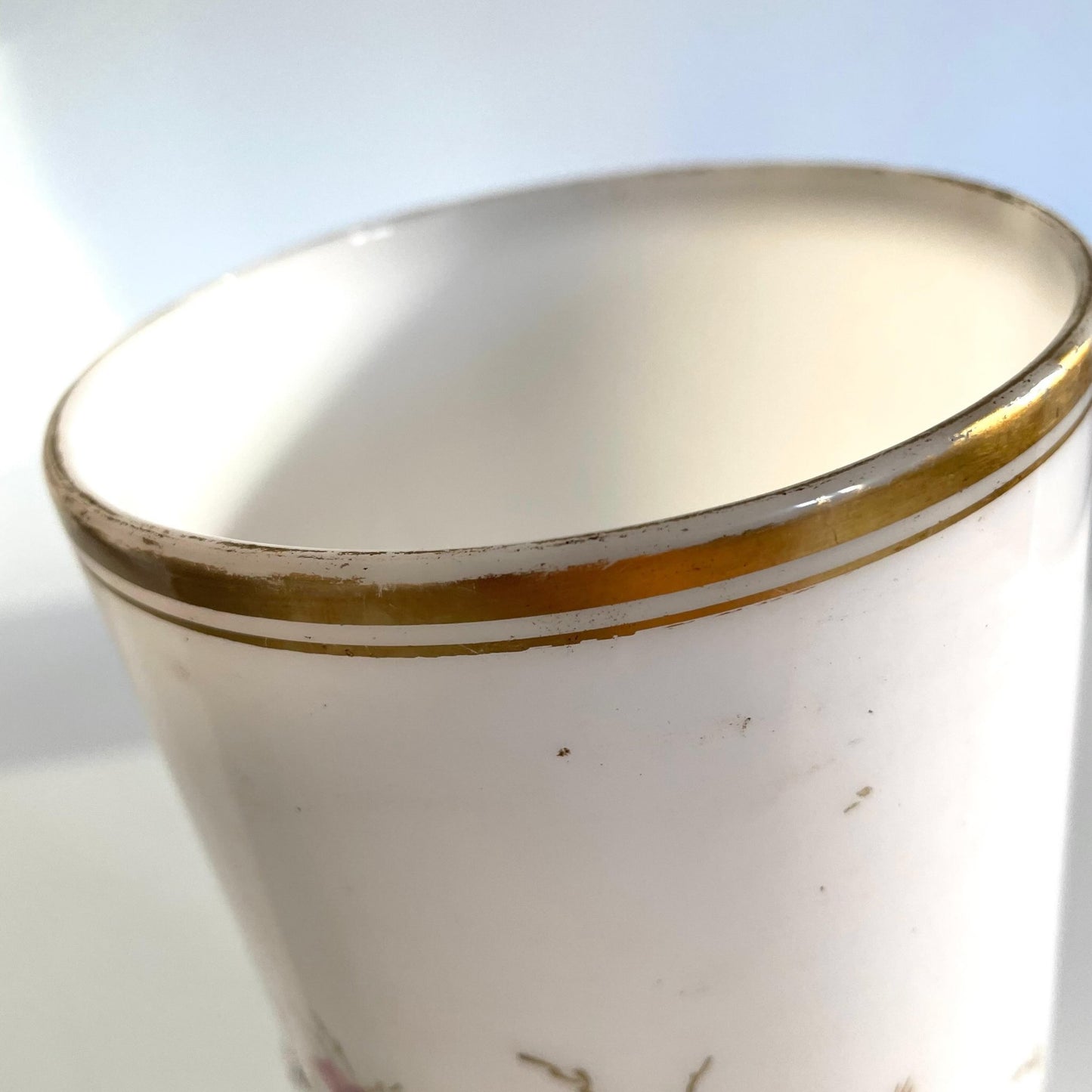 日本語: 19世紀後期の白いオパリンガラスの花瓶。フランス製の可能性が高く、手描きの花模様とカメオスタイルの精巧なブロンズ製女性肖像が特徴。 ; English: White opaline vase from the late 19th century, likely of French origin, featuring a delicate hand-painted floral design and a finely detailed bronze cameo-style portrait of a woman. ; Français: Vase en opaline blanche de la fin du XIXe siècle, très probablement d'origine française, avec un motif floral peint à la main et un portrait féminin en bronze finement détaillé dans un style camée.