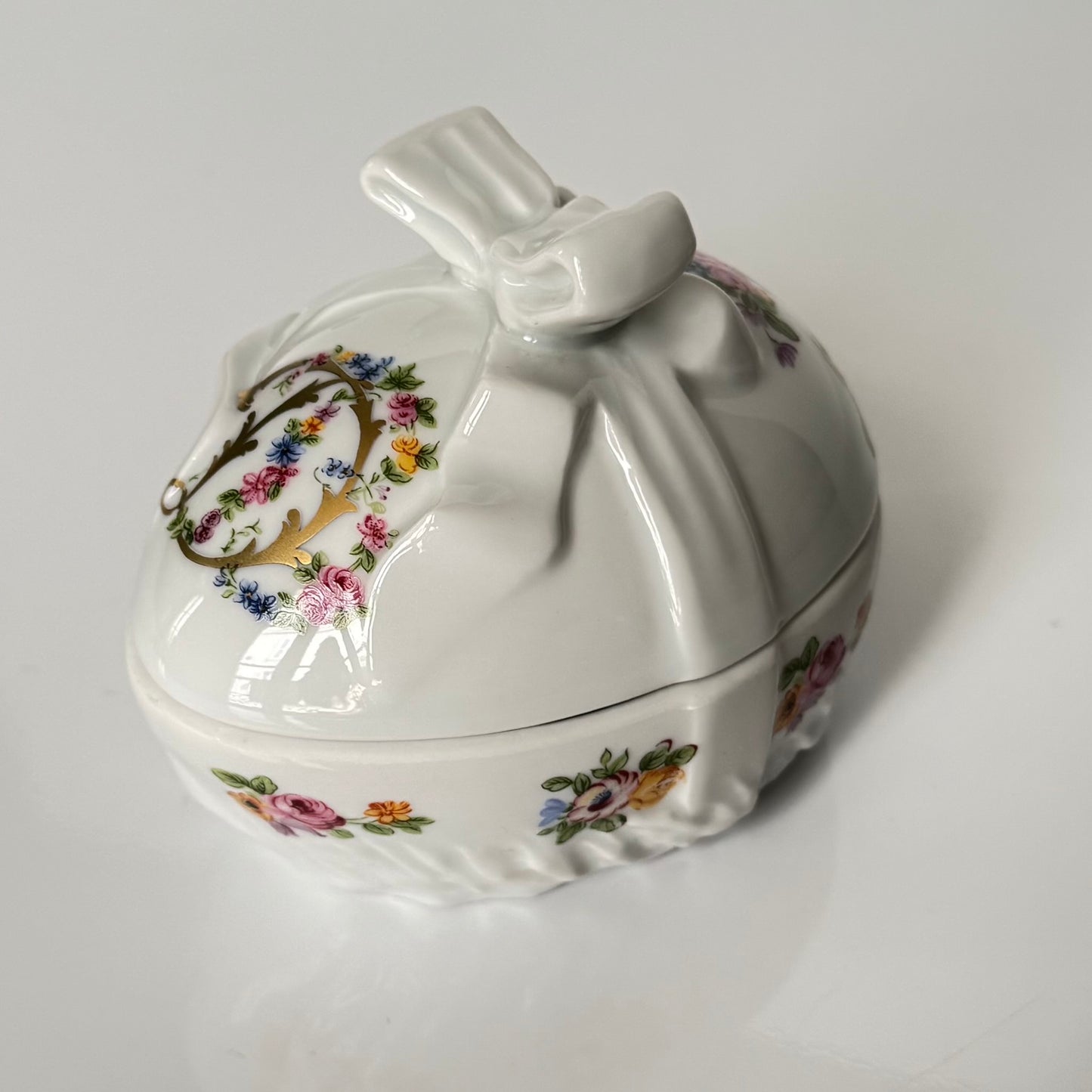 Vintage porcelain egg-shaped box by APILCO, inspired by the 18th-century Sèvres du Barry service. Features ribbon details, floral patterns, and “DB” initials in elegant design