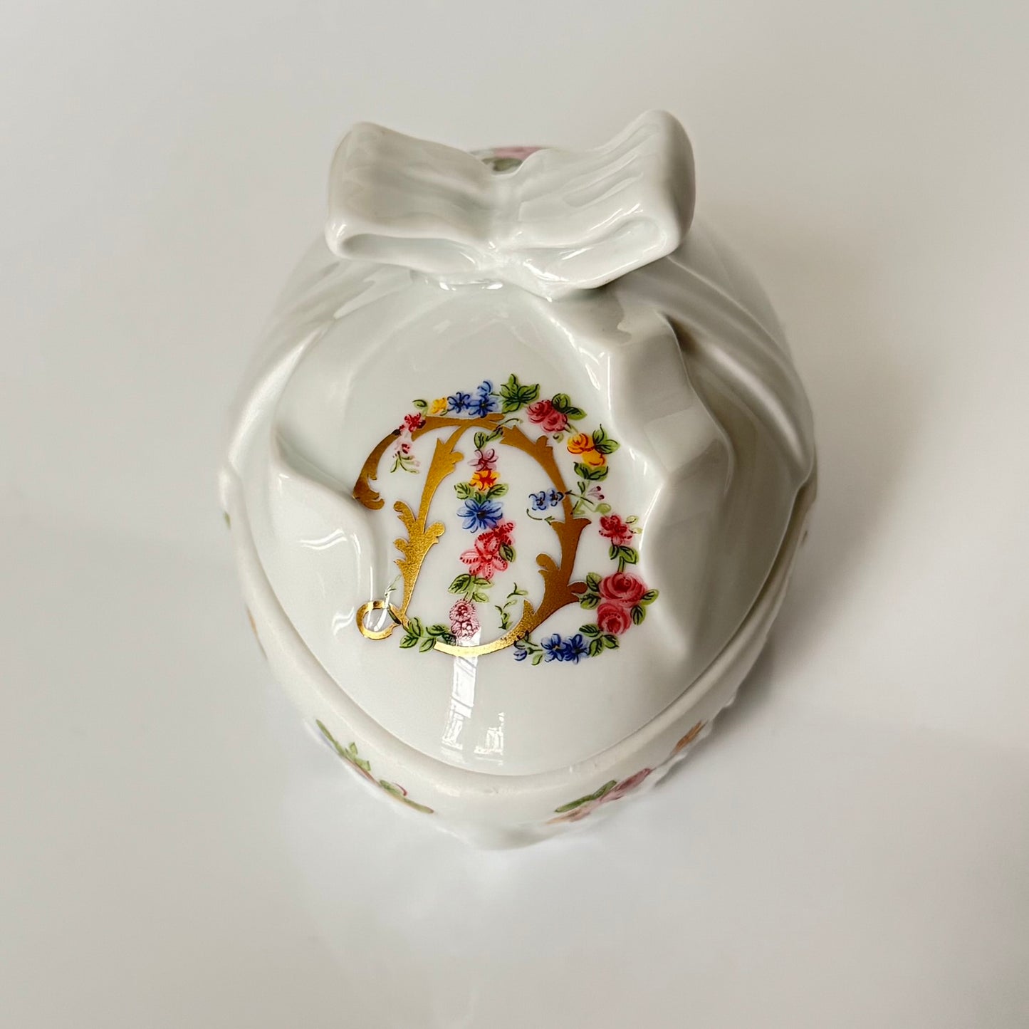 Vintage porcelain egg-shaped box by APILCO, inspired by the 18th-century Sèvres du Barry service. Features ribbon details, floral patterns, and “DB” initials in elegant design
