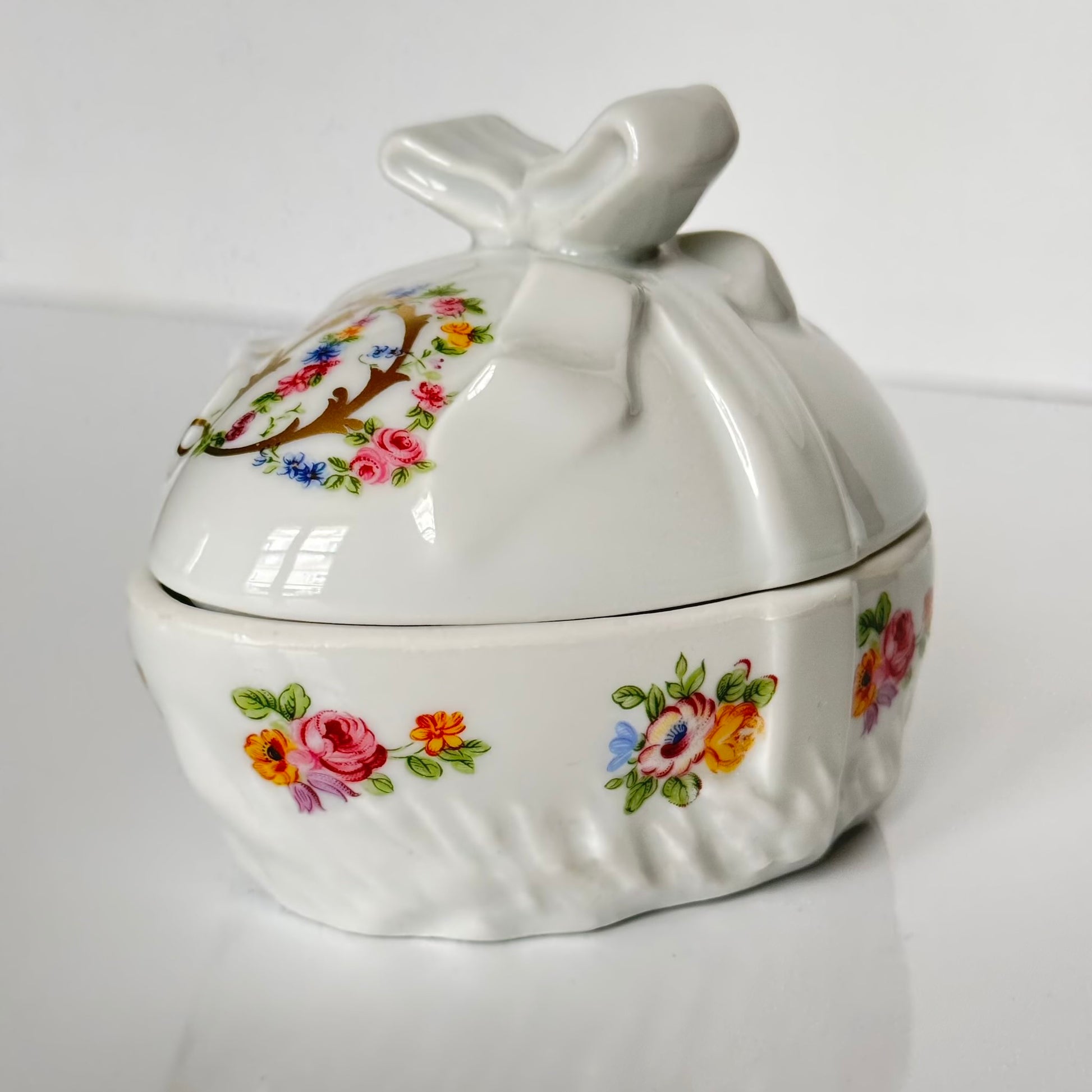 Vintage porcelain egg-shaped box by APILCO, inspired by the 18th-century Sèvres du Barry service. Features ribbon details, floral patterns, and “DB” initials in elegant design