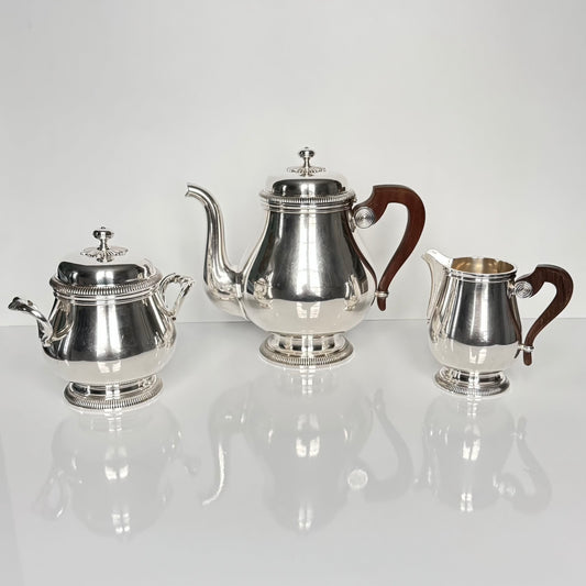 English: Christofle “Lauzun” silver-plated tea set with teapot, sugar bowl, and creamer, mid-20th century, featuring wooden handles and elegant minimalist design. ; Français : Service à thé Christofle « Lauzun » en métal argenté avec théière, sucrier et pot à lait, milieu du XXᵉ siècle, avec poignées en bois et design élégant et épuré. ; 日本語: クリストフル「Lauzun」銀メッキ ティーセット（ティーポット、シュガーボウル、クリーマー）。20世紀中頃の作品で、木製ハンドルと上品でシンプルなデザインが特徴。
