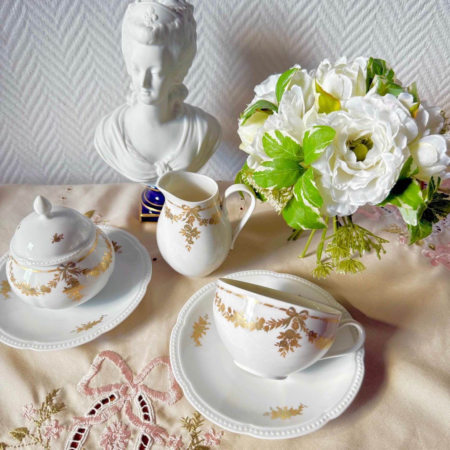 English: Vintage Bavaria “H&Co Selb” egoïste tea set with tea cup, two saucers, creamer, and sugar bowl, decorated with gilded bows and garlands. ; Français : Service à thé égoïste vintage Bavaria “H&Co Selb” comprenant tasse, 2 sous-tasses, pot à lait et sucrier, décoré de nœuds et guirlandes dorés. ; 日本語: ヴィンテージ ババリア「H&Co Selb」エゴイスト ティーセット（ティーカップ、ソーサー2枚、クリーマー、シュガーボウル）、金彩のリボンとガーランド装飾付き。