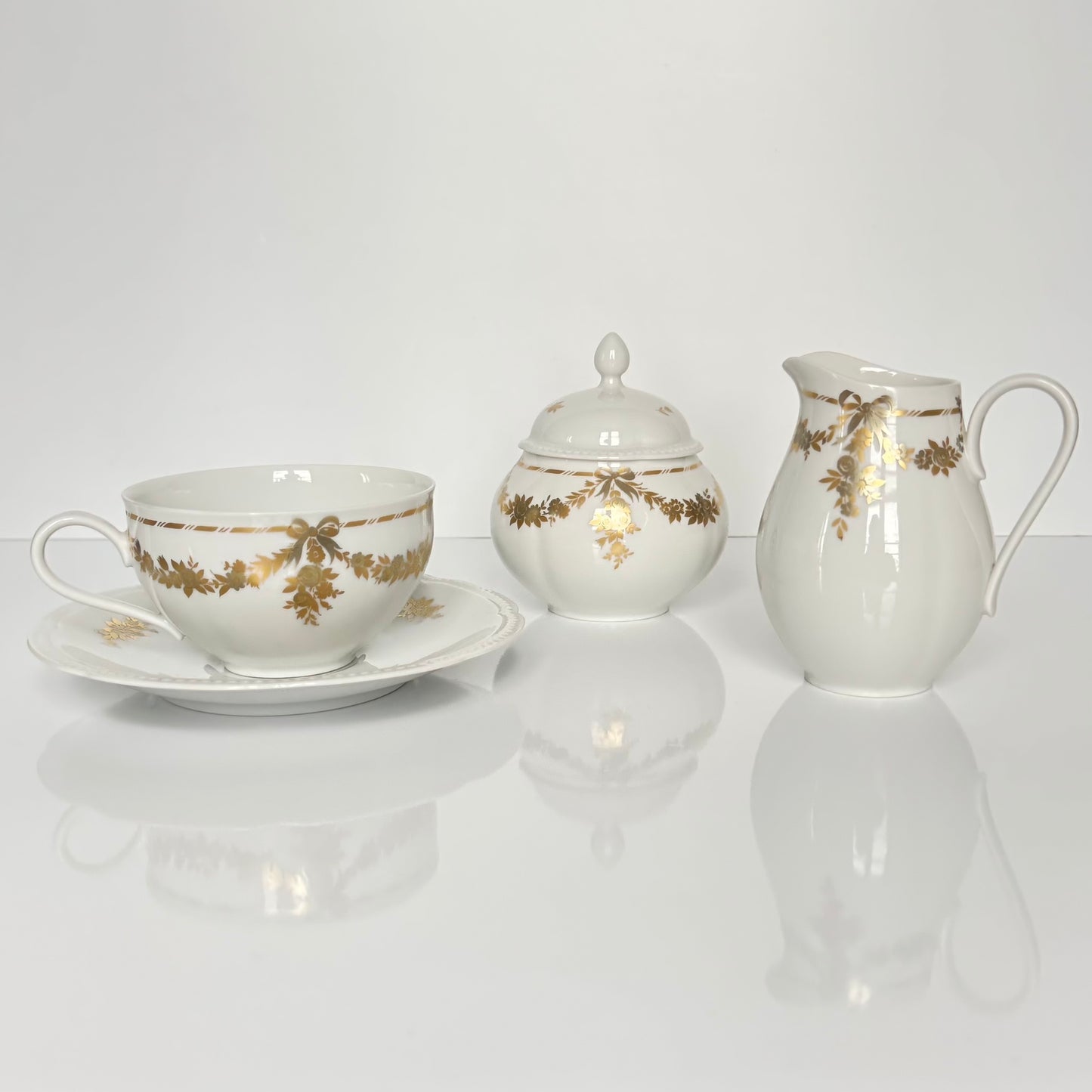 English: Vintage Bavaria “H&Co Selb” egoïste tea set with tea cup, two saucers, creamer, and sugar bowl, decorated with gilded bows and garlands. ; Français : Service à thé égoïste vintage Bavaria “H&Co Selb” comprenant tasse, 2 sous-tasses, pot à lait et sucrier, décoré de nœuds et guirlandes dorés. ; 日本語: ヴィンテージ ババリア「H&Co Selb」エゴイスト ティーセット（ティーカップ、ソーサー2枚、クリーマー、シュガーボウル）、金彩のリボンとガーランド装飾付き。