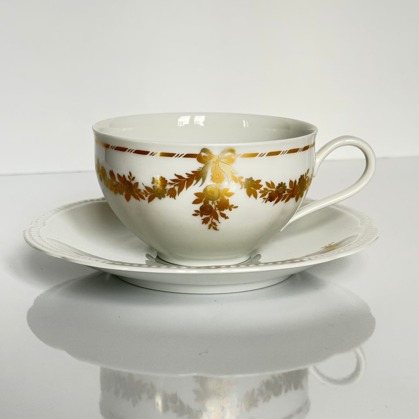 English: Vintage Bavaria “H&Co Selb” egoïste tea set with tea cup, two saucers, creamer, and sugar bowl, decorated with gilded bows and garlands. ; Français : Service à thé égoïste vintage Bavaria “H&Co Selb” comprenant tasse, 2 sous-tasses, pot à lait et sucrier, décoré de nœuds et guirlandes dorés. ; 日本語: ヴィンテージ ババリア「H&Co Selb」エゴイスト ティーセット（ティーカップ、ソーサー2枚、クリーマー、シュガーボウル）、金彩のリボンとガーランド装飾付き。