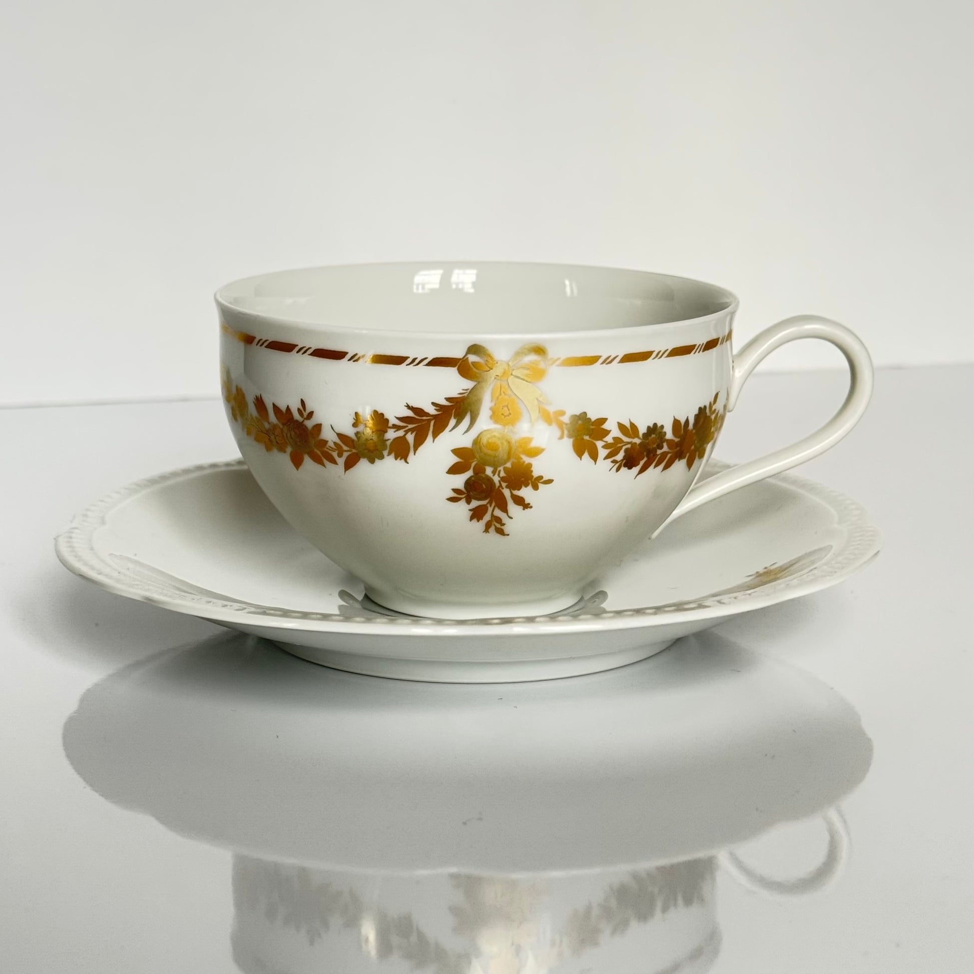 English: Vintage Bavaria “H&Co Selb” egoïste tea set with tea cup, two saucers, creamer, and sugar bowl, decorated with gilded bows and garlands. ; Français : Service à thé égoïste vintage Bavaria “H&Co Selb” comprenant tasse, 2 sous-tasses, pot à lait et sucrier, décoré de nœuds et guirlandes dorés. ; 日本語: ヴィンテージ ババリア「H&Co Selb」エゴイスト ティーセット（ティーカップ、ソーサー2枚、クリーマー、シュガーボウル）、金彩のリボンとガーランド装飾付き。