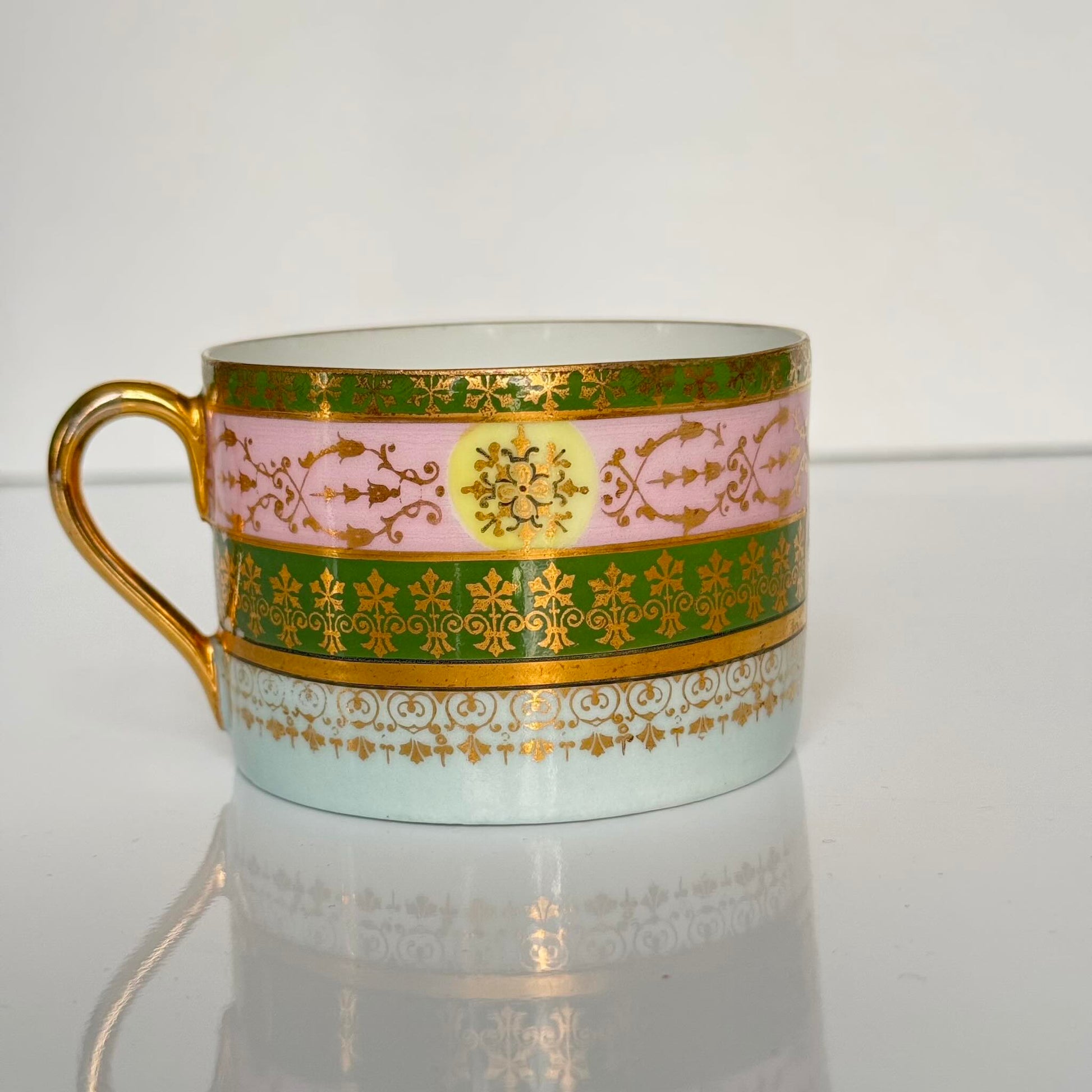 Porcelain cup and saucer set inspired by 18th-century Sèvres style, with delicate pink and green hues and gilded details.
