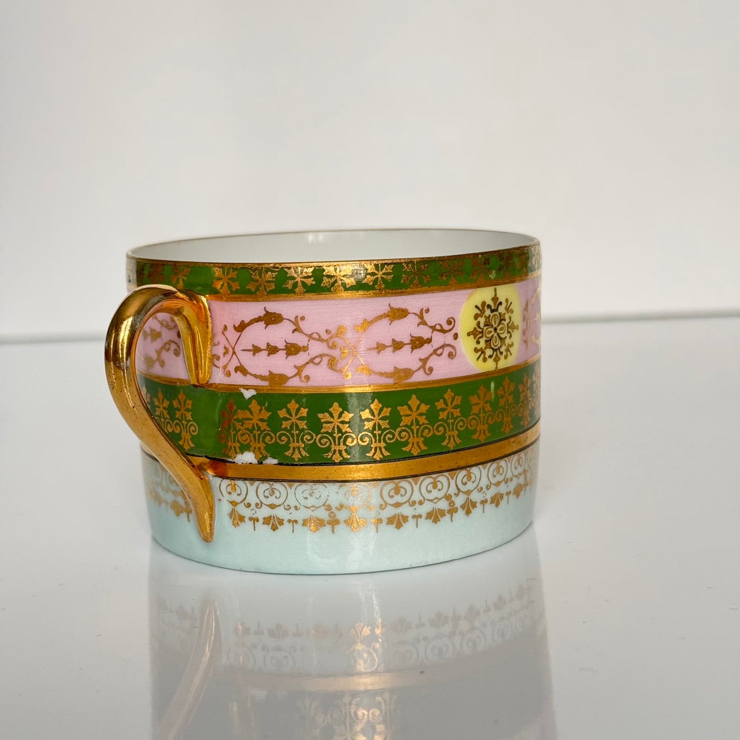 Porcelain cup and saucer set inspired by 18th-century Sèvres style, with delicate pink and green hues and gilded details.