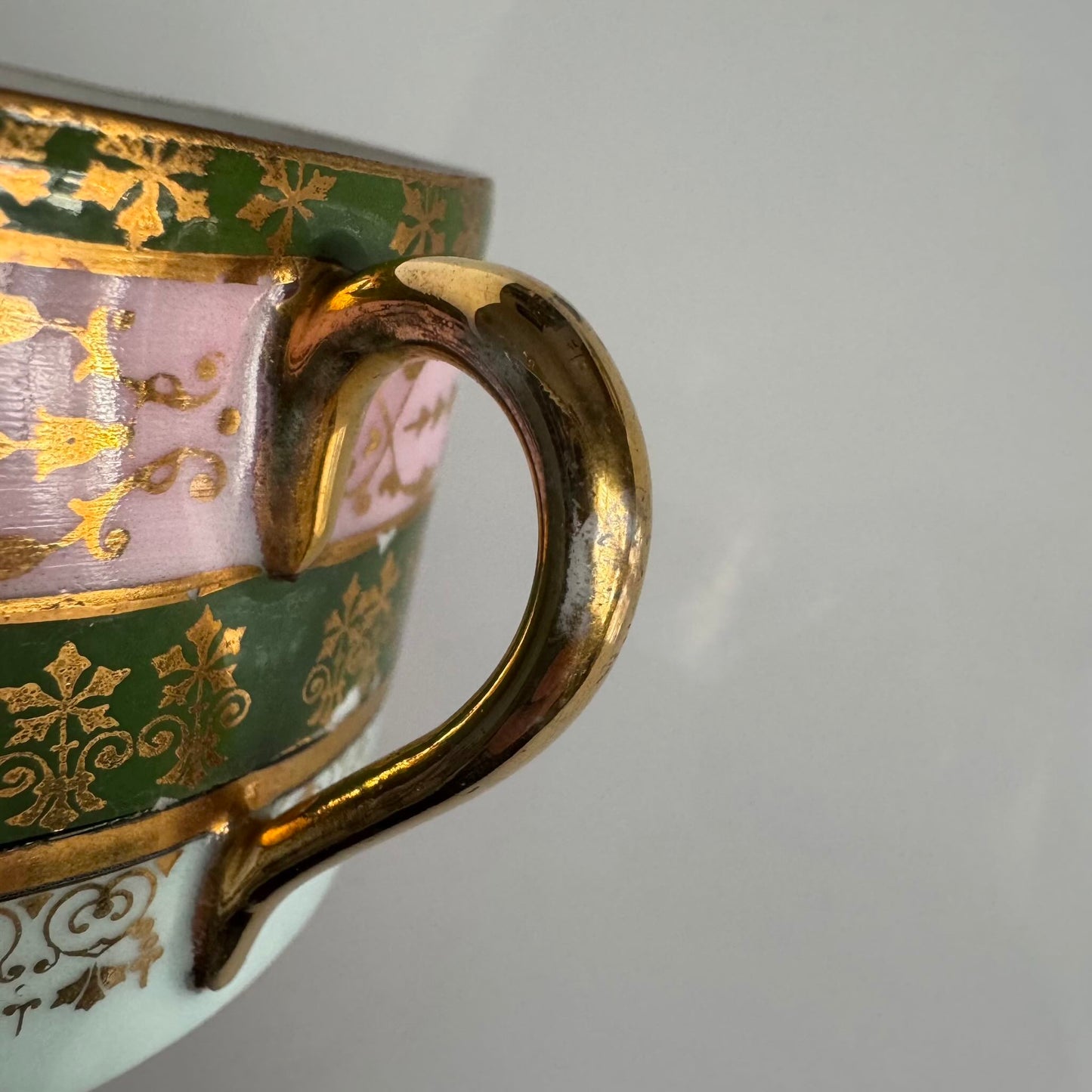 Porcelain cup and saucer set inspired by 18th-century Sèvres style, with delicate pink and green hues and gilded details.