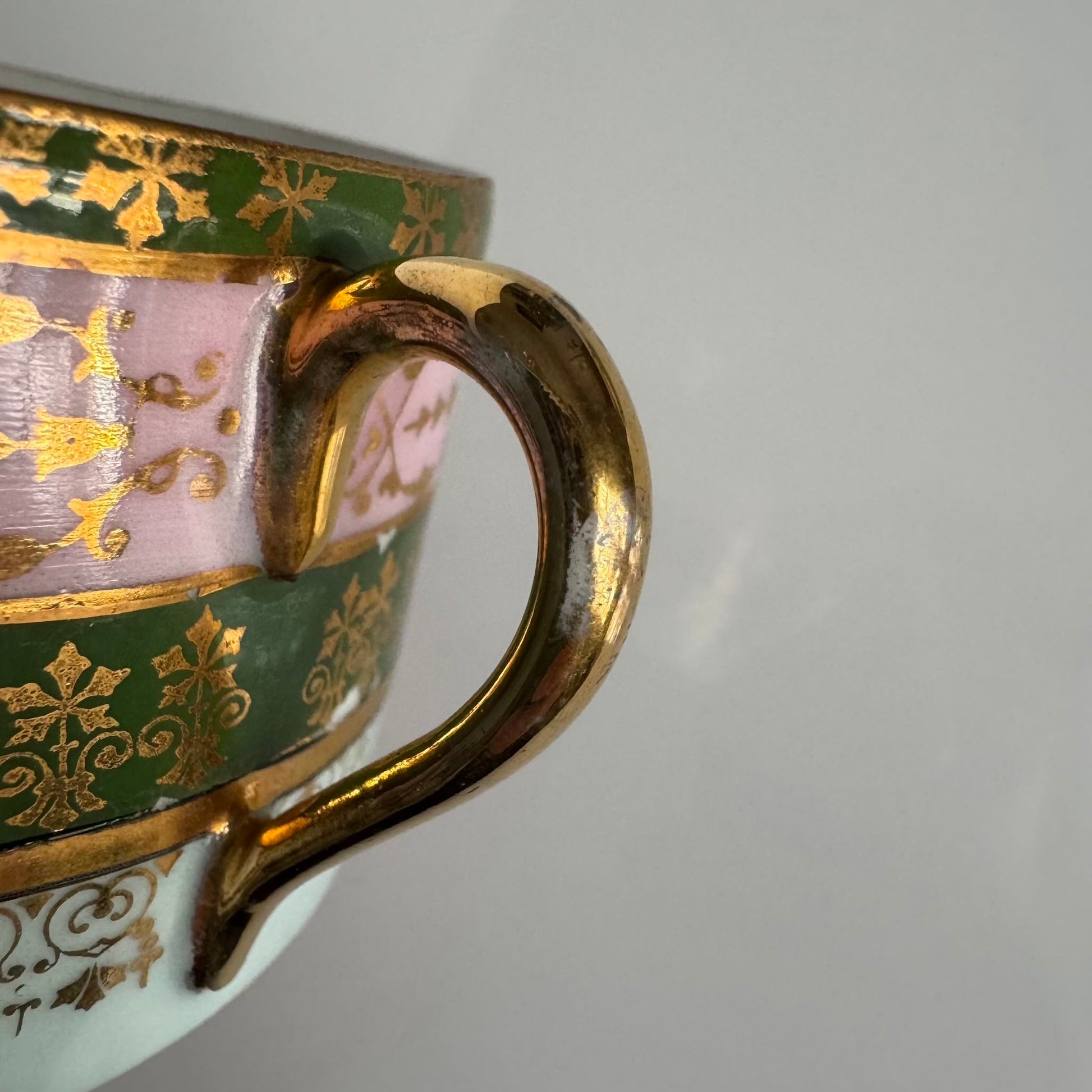 Porcelain cup and saucer set inspired by 18th-century Sèvres style, with delicate pink and green hues and gilded details.