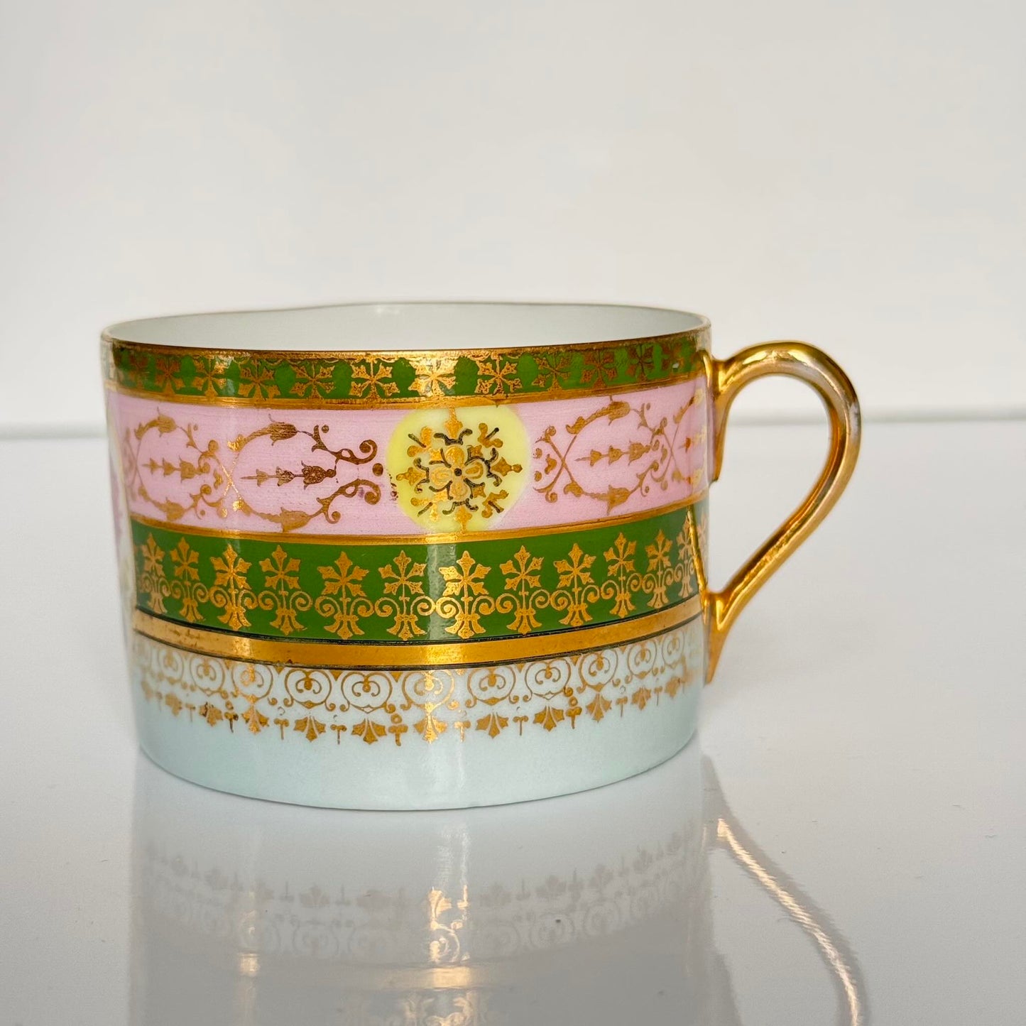 Porcelain cup and saucer set inspired by 18th-century Sèvres style, with delicate pink and green hues and gilded details.