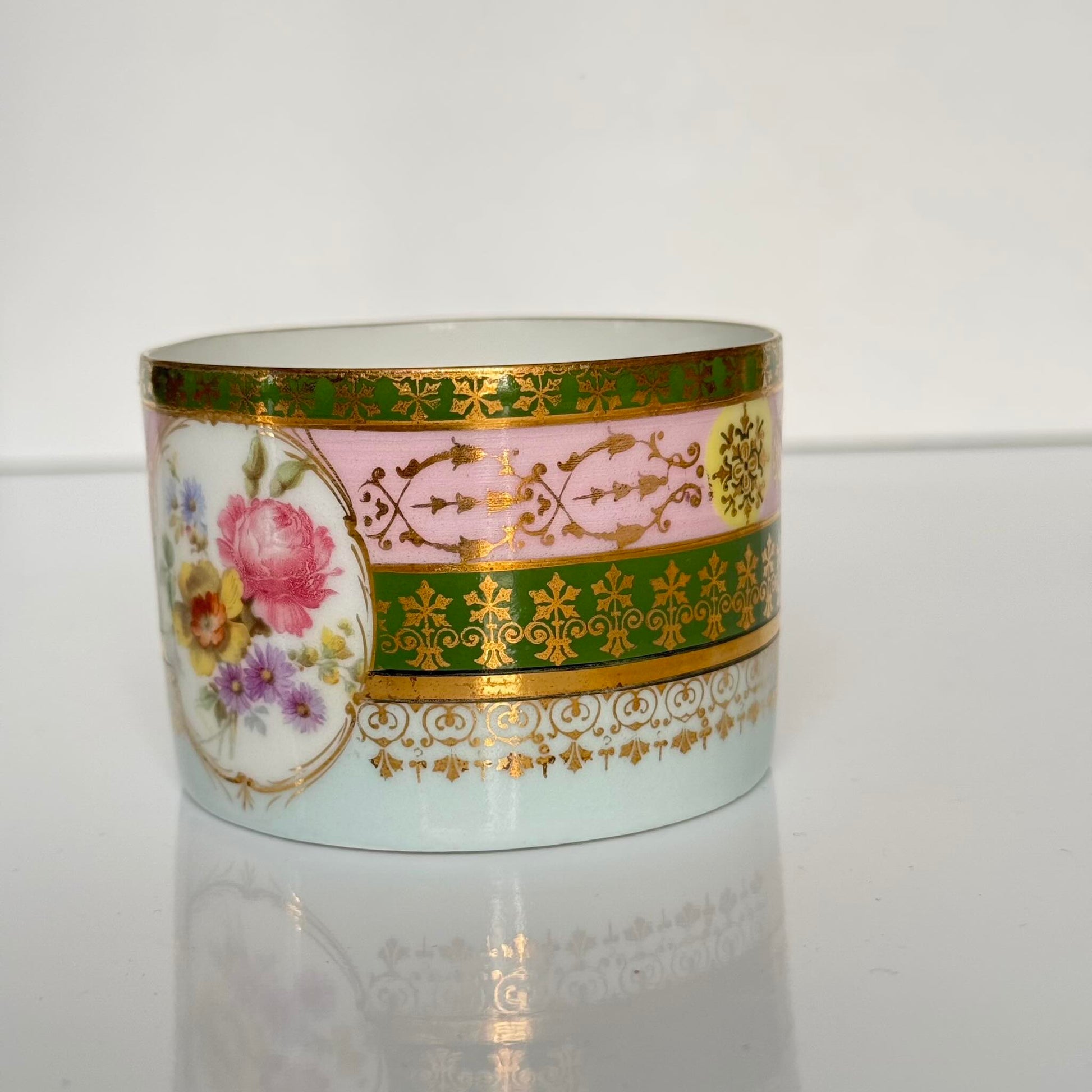 Porcelain cup and saucer set inspired by 18th-century Sèvres style, with delicate pink and green hues and gilded details.