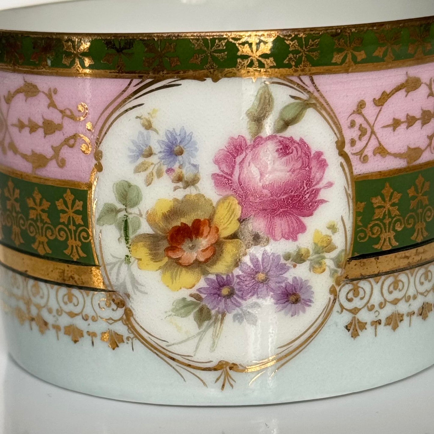 Porcelain cup and saucer set inspired by 18th-century Sèvres style, with delicate pink and green hues and gilded details.