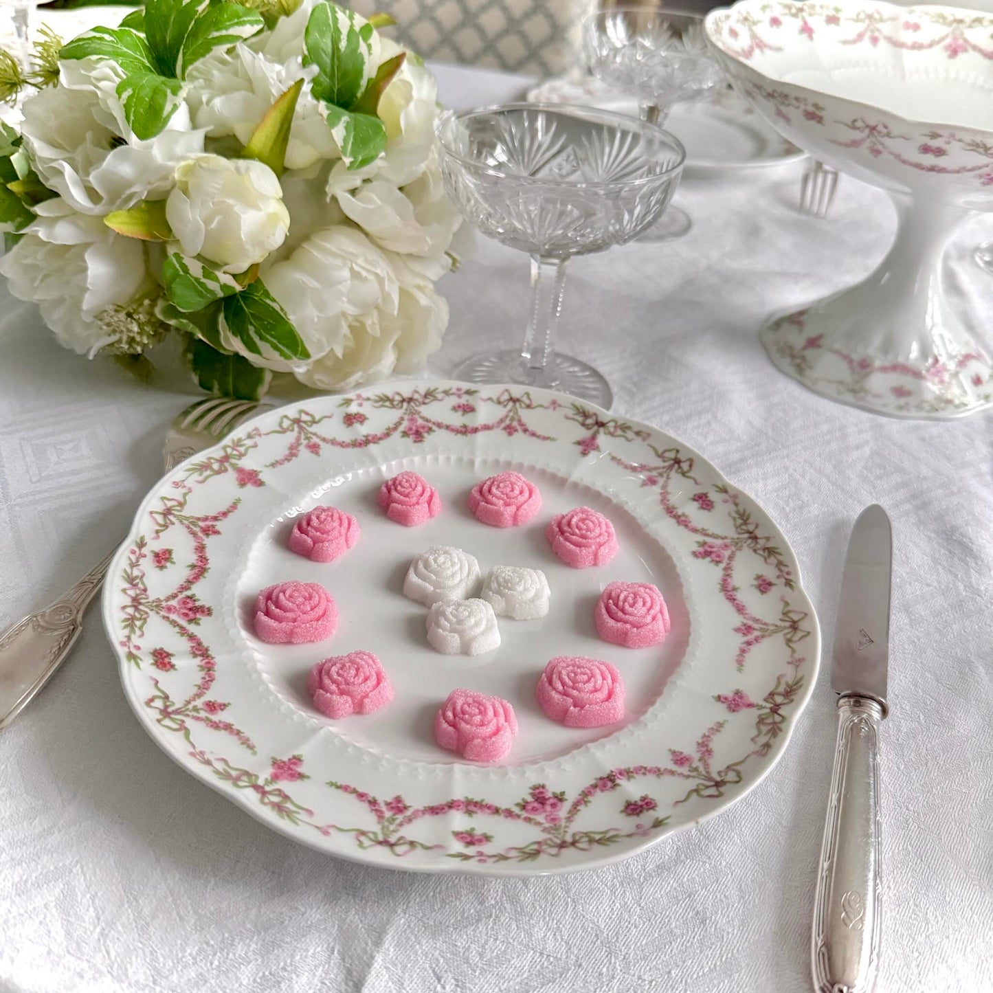 Set of two antique Limoges porcelain dessert plates by Ahrenfeldt, decorated with ribbon motifs and floral garlands, late 19th to early 20th century.
