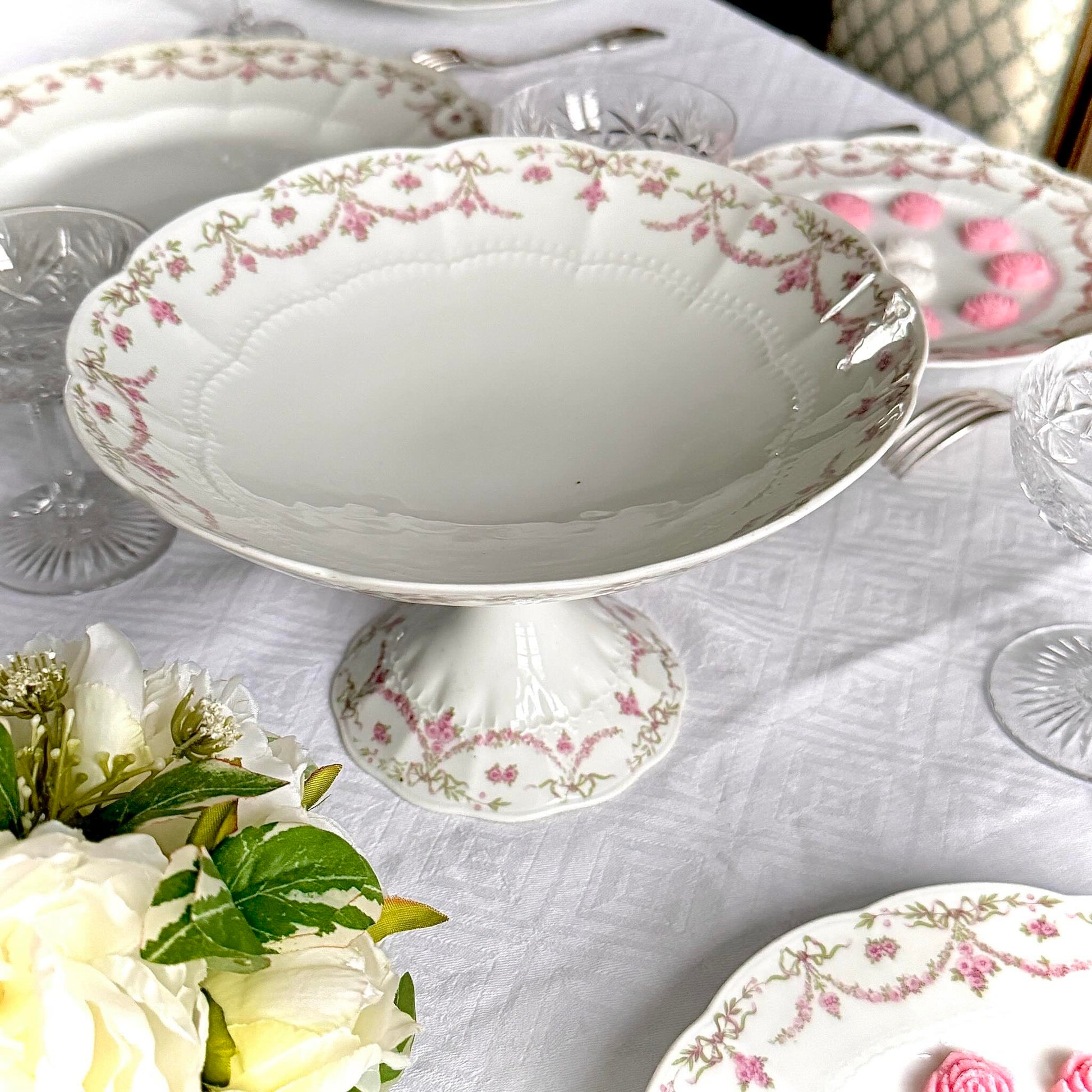 English: Ahrenfeldt Limoges porcelain compote on pedestal with ribbon and floral garland decoration, late 19th to early 20th century, France. ;
Français : Compotier en porcelaine de Limoges Ahrenfeldt sur piédouche, décor de rubans et guirlandes de fleurs, fin XIXᵉ – début XXᵉ siècle. ;
日本語: アーレンフェルト製 リモージュ磁器の脚付きコンポティエ（フルーツスタンド）。リボンとガーランドの装飾、19世紀末〜20世紀初頭 フランス。