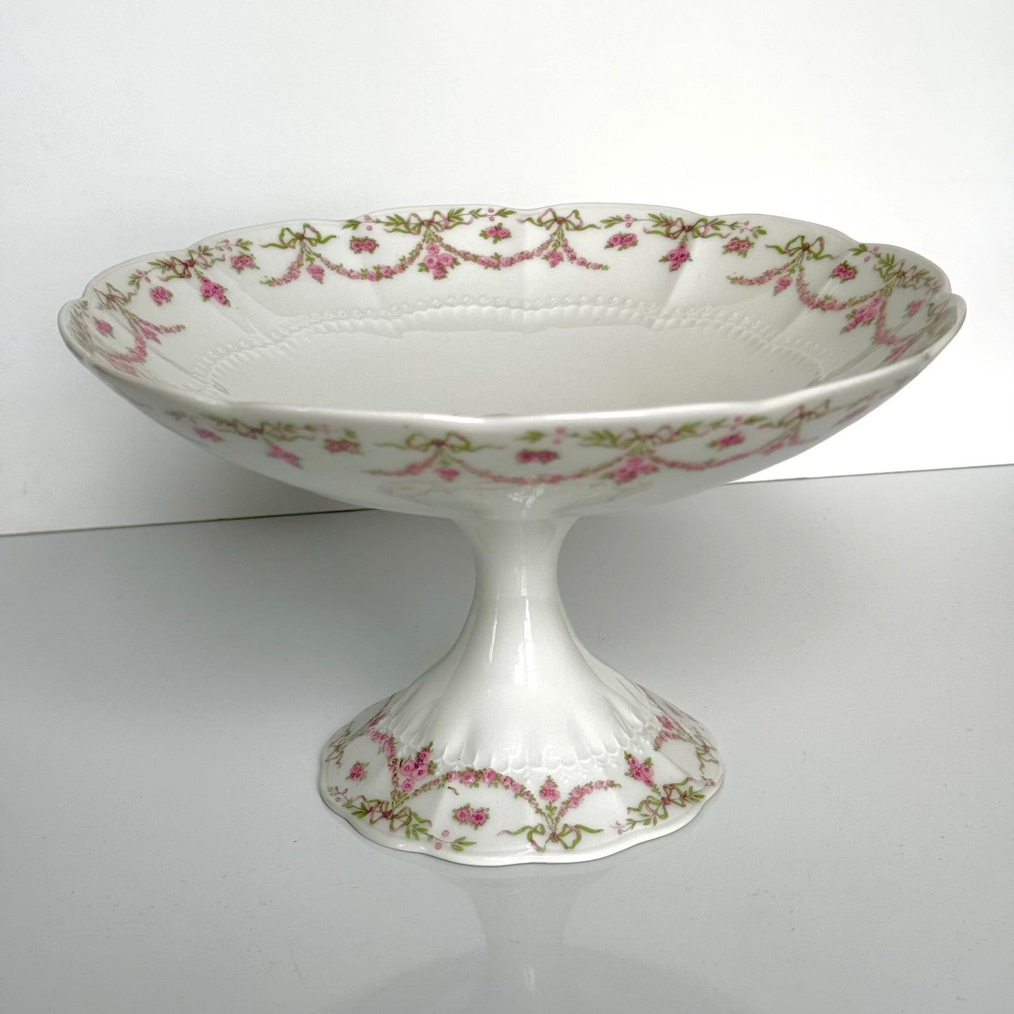 English: Ahrenfeldt Limoges porcelain compote on pedestal with ribbon and floral garland decoration, late 19th to early 20th century, France. ;
Français : Compotier en porcelaine de Limoges Ahrenfeldt sur piédouche, décor de rubans et guirlandes de fleurs, fin XIXᵉ – début XXᵉ siècle. ;
日本語: アーレンフェルト製 リモージュ磁器の脚付きコンポティエ（フルーツスタンド）。リボンとガーランドの装飾、19世紀末〜20世紀初頭 フランス。