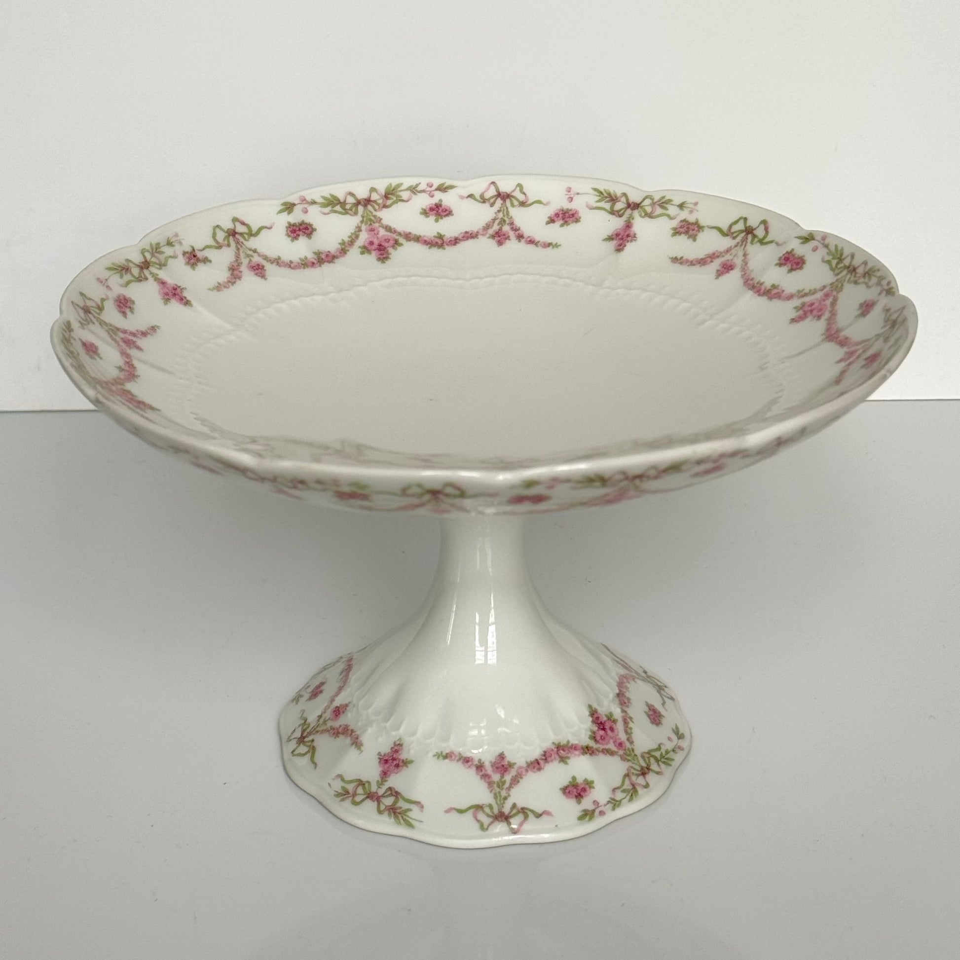 English: Ahrenfeldt Limoges porcelain compote on pedestal with ribbon and floral garland decoration, late 19th to early 20th century, France. ;
Français : Compotier en porcelaine de Limoges Ahrenfeldt sur piédouche, décor de rubans et guirlandes de fleurs, fin XIXᵉ – début XXᵉ siècle. ;
日本語: アーレンフェルト製 リモージュ磁器の脚付きコンポティエ（フルーツスタンド）。リボンとガーランドの装飾、19世紀末〜20世紀初頭 フランス。