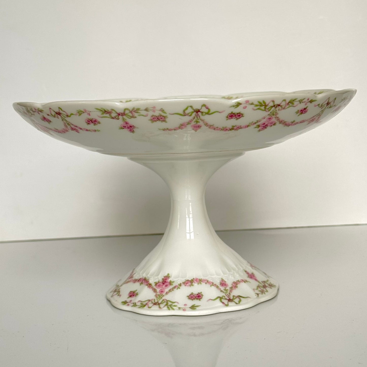 English: Ahrenfeldt Limoges porcelain compote on pedestal with ribbon and floral garland decoration, late 19th to early 20th century, France. ;
Français : Compotier en porcelaine de Limoges Ahrenfeldt sur piédouche, décor de rubans et guirlandes de fleurs, fin XIXᵉ – début XXᵉ siècle. ;
日本語: アーレンフェルト製 リモージュ磁器の脚付きコンポティエ（フルーツスタンド）。リボンとガーランドの装飾、19世紀末〜20世紀初頭 フランス。