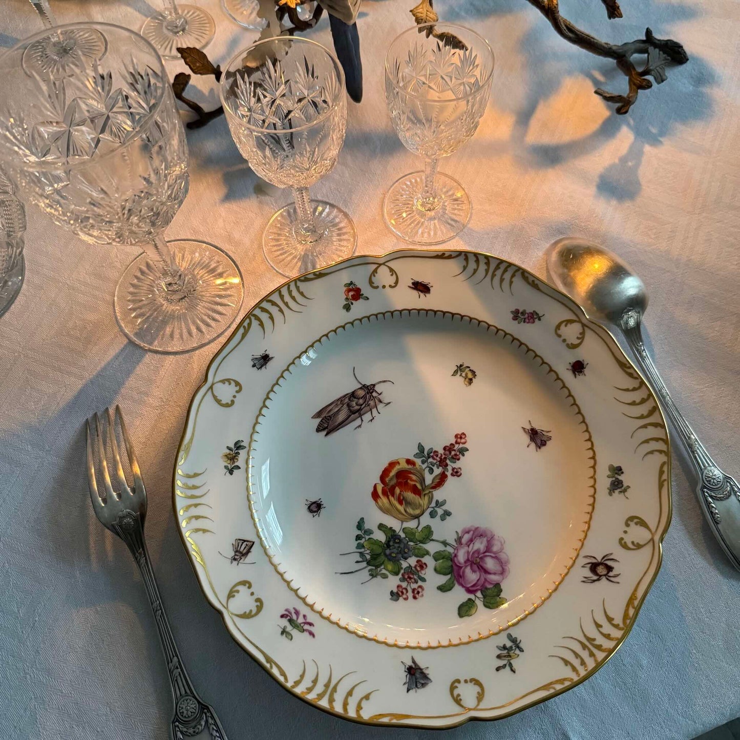 Antique KPM Berlin hand-painted porcelain soup plate featuring a floral bouquet, insects, and rich gold detailing, late 19th century.