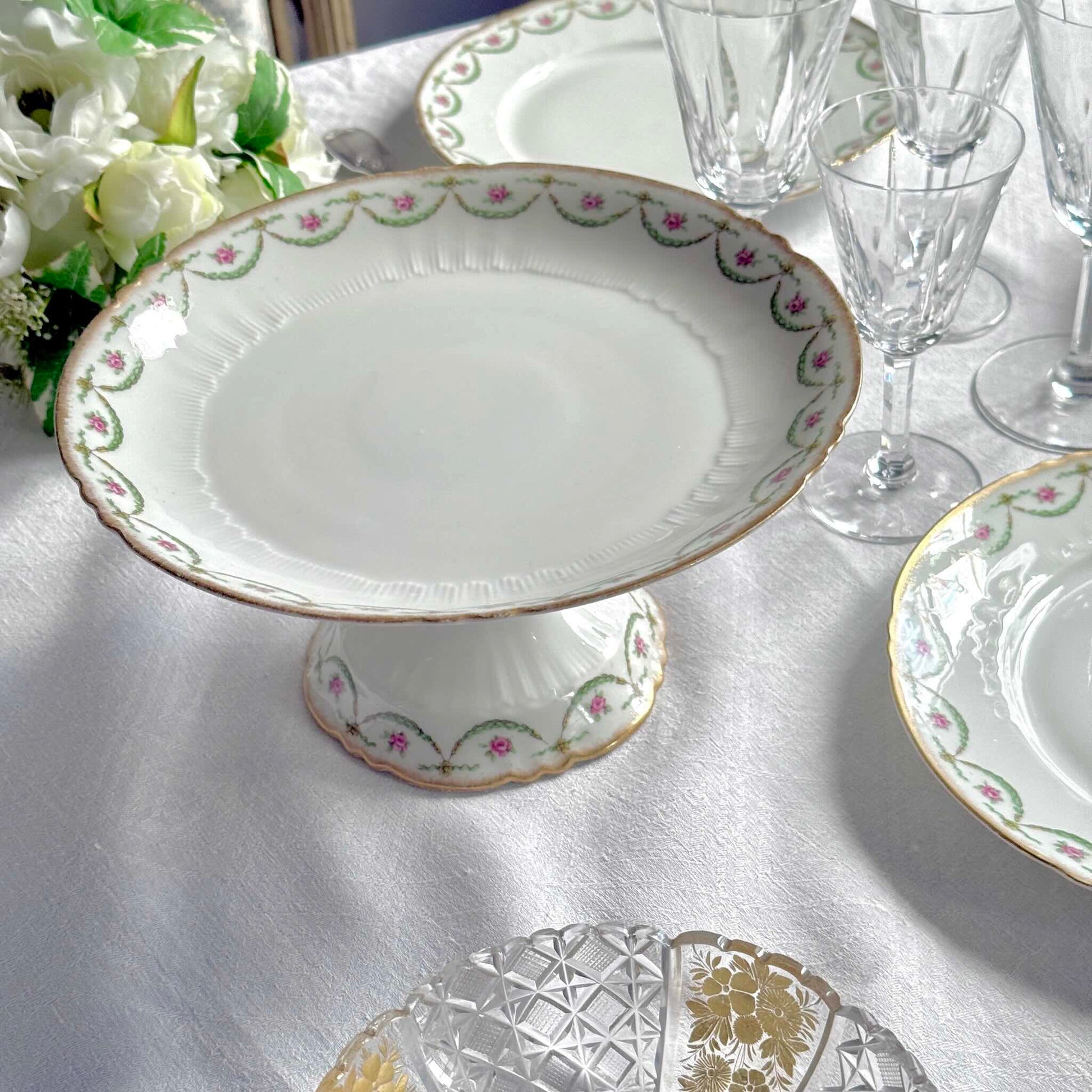 Antique Limoges porcelain compotier on pedestal, pink rose floral pattern and gold trim, late 19th or early 20th century France.