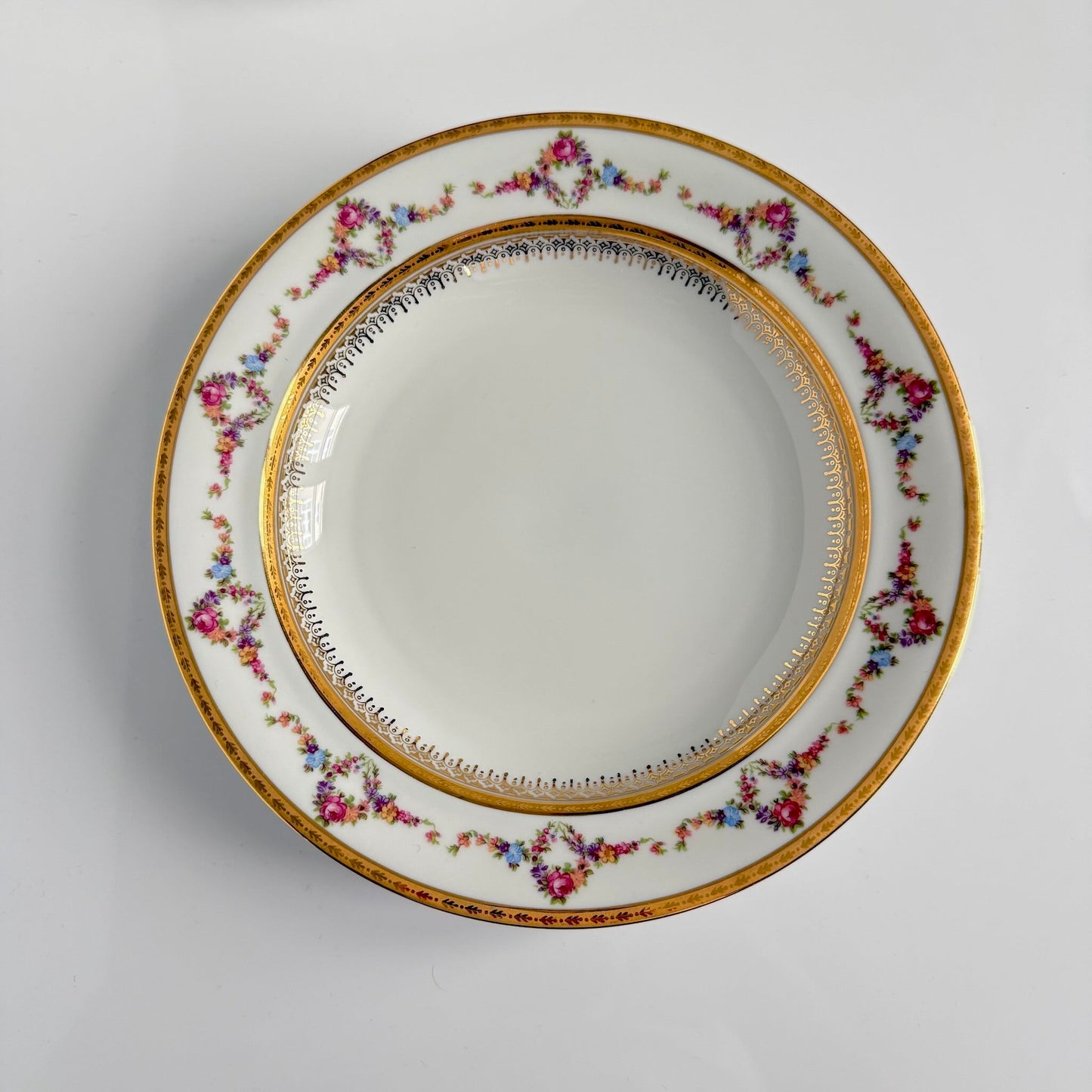 Set of two Limoges P.P. porcelain soup plates featuring floral garlands, wreaths, and rich gilding, 20th century France.