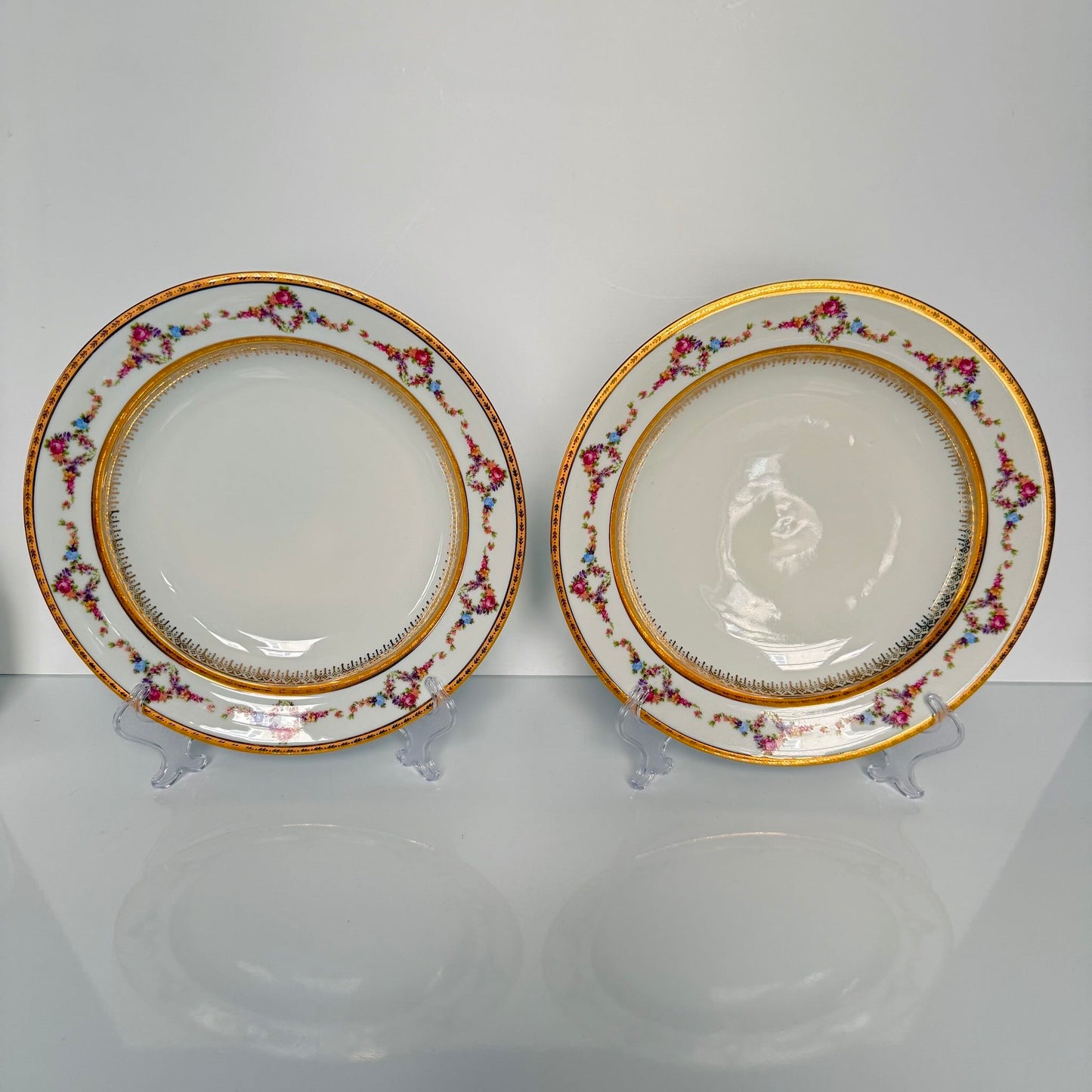 Set of two Limoges P.P. porcelain soup plates featuring floral garlands, wreaths, and rich gilding, 20th century France.
