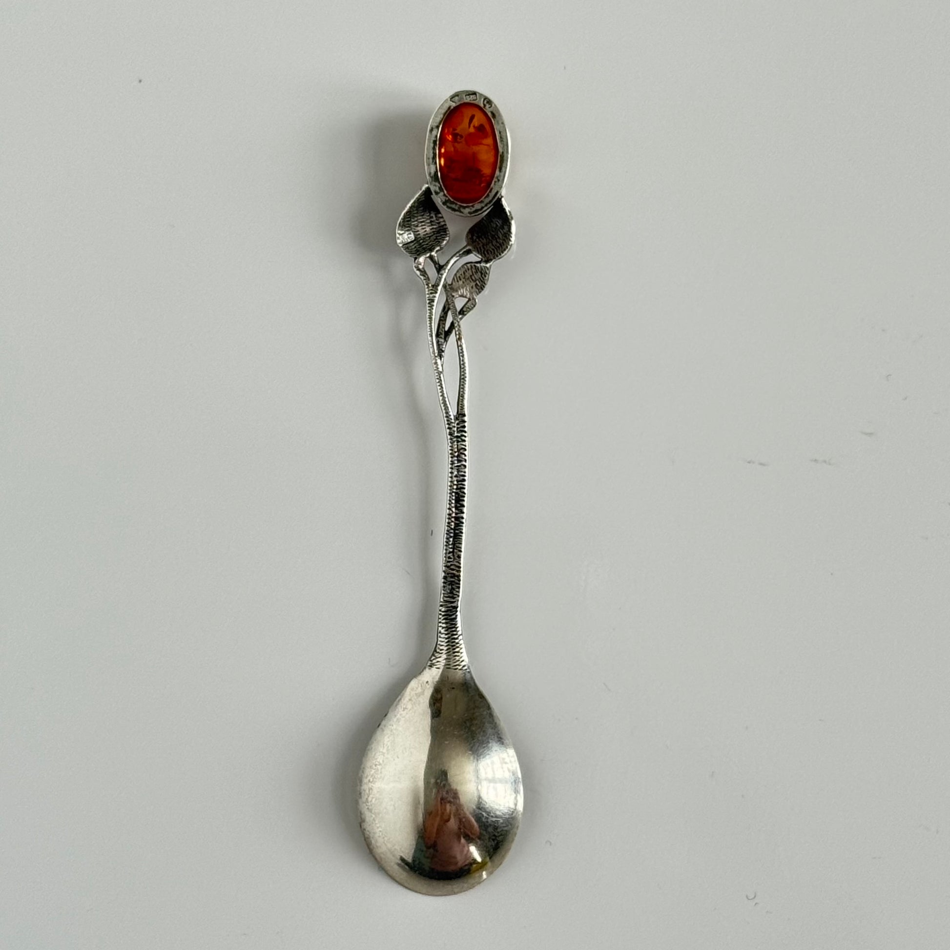 English: Art Nouveau style silver spoon with amber accent and delicate leaf motif, in 925 silver ; 日本語: アンバー（琥珀）付きアール・ヌーヴォー様式のシルバースプーン、繊細な葉モチーフと925シルバーの装飾 ; Français: Cuillère en argent style Art Nouveau avec ambre, décorée d’un motif feuillage délicat en argent 925.