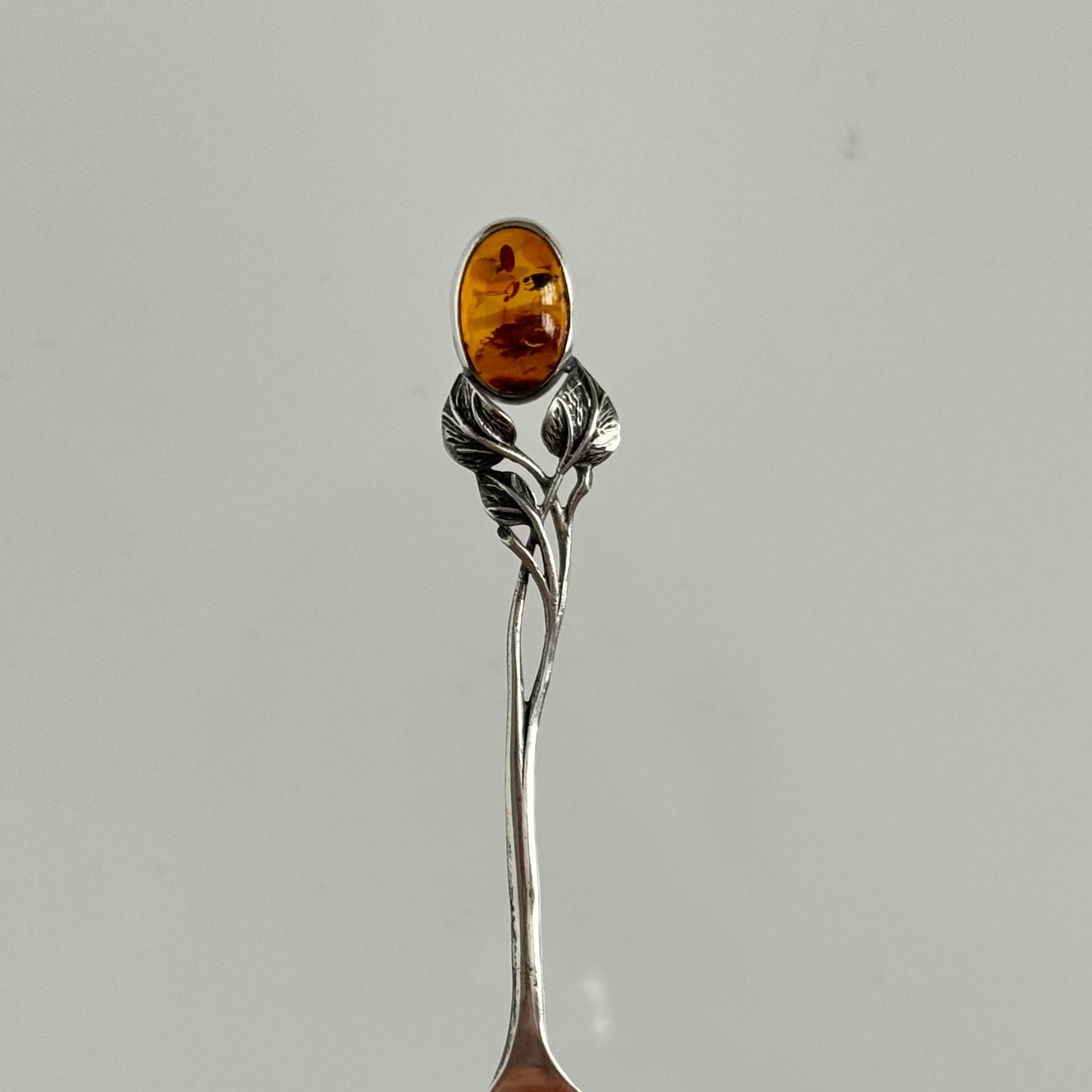 English: Art Nouveau style silver spoon with amber accent and delicate leaf motif, in 925 silver ; 日本語: アンバー（琥珀）付きアール・ヌーヴォー様式のシルバースプーン、繊細な葉モチーフと925シルバーの装飾 ; Français: Cuillère en argent style Art Nouveau avec ambre, décorée d’un motif feuillage délicat en argent 925.