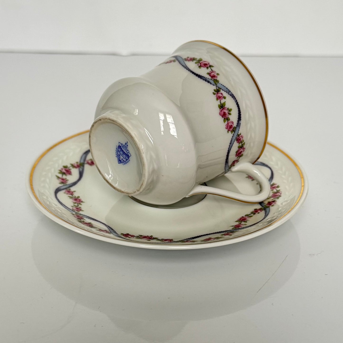 English: Bernardaud Limoges porcelain cup and saucer set, blue ribbon and rose garland design, early 20th century, signed B.H Cadeaux and B&Co; 日本語: ベルナルド・リモージュのポーセリン製カップ＆ソーサー、ブルーリボンとバラのガーランド模様、20世紀前期製造、B.H CadeauxおよびB&Coのサイン入り; Français: Ensemble tasse et soucoupe en porcelaine de Limoges par Bernardaud, décor de ruban bleu et guirlande de roses, début du XXe siècle, signé B.H Cadeaux et B&Co.