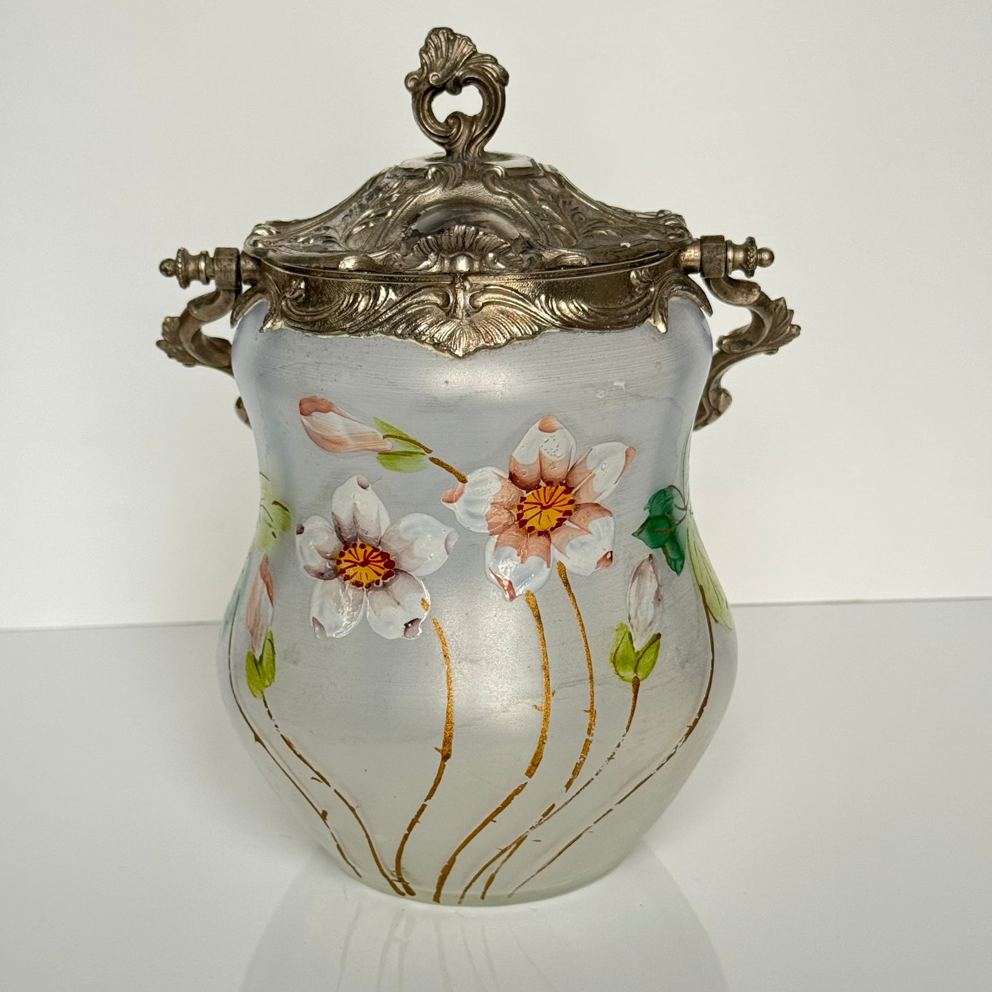 English: Hand-painted glass biscuit jar from the late 19th to early 20th century, featuring floral motifs and Rocaille-style metal mounts from the Art Nouveau period; 日本語: 19世紀後期から20世紀初頭のガラス製ビスケットジャー、アール・ヌーヴォー様式のロカイユ風金属装飾と手描きの花柄入り； Français: Pot à biscuits en verre peint à la main, fin XIXᵉ – début XXᵉ siècle, décor floral et monture en métal de style rocaille de l’époque Art Nouveau.
