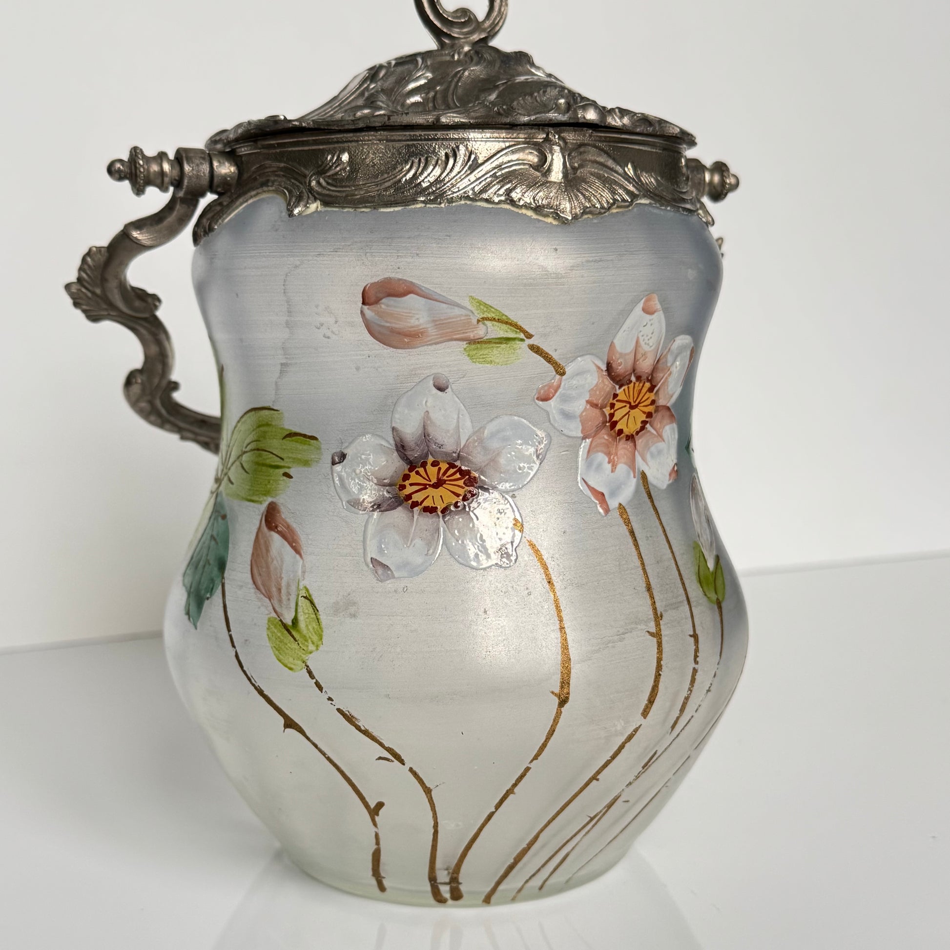 English: Hand-painted glass biscuit jar from the late 19th to early 20th century, featuring floral motifs and Rocaille-style metal mounts from the Art Nouveau period; 日本語: 19世紀後期から20世紀初頭のガラス製ビスケットジャー、アール・ヌーヴォー様式のロカイユ風金属装飾と手描きの花柄入り； Français: Pot à biscuits en verre peint à la main, fin XIXᵉ – début XXᵉ siècle, décor floral et monture en métal de style rocaille de l’époque Art Nouveau.
