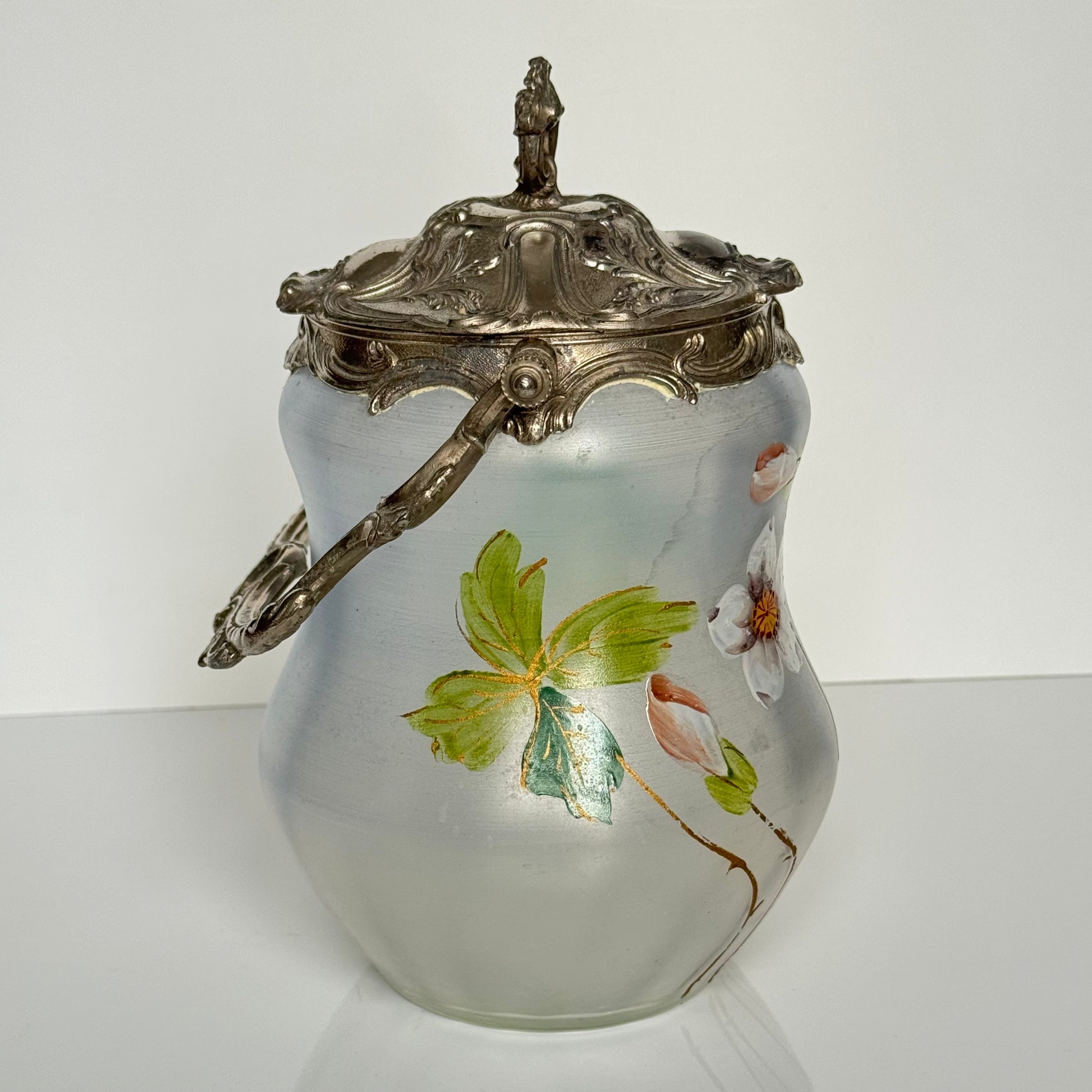 English: Hand-painted glass biscuit jar from the late 19th to early 20th century, featuring floral motifs and Rocaille-style metal mounts from the Art Nouveau period; 日本語: 19世紀後期から20世紀初頭のガラス製ビスケットジャー、アール・ヌーヴォー様式のロカイユ風金属装飾と手描きの花柄入り； Français: Pot à biscuits en verre peint à la main, fin XIXᵉ – début XXᵉ siècle, décor floral et monture en métal de style rocaille de l’époque Art Nouveau.