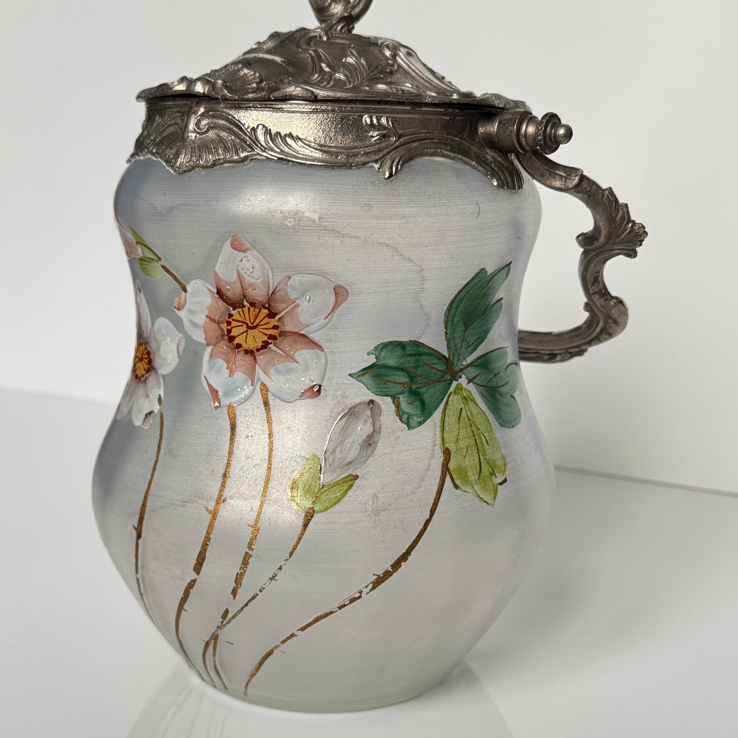 English: Hand-painted glass biscuit jar from the late 19th to early 20th century, featuring floral motifs and Rocaille-style metal mounts from the Art Nouveau period; 日本語: 19世紀後期から20世紀初頭のガラス製ビスケットジャー、アール・ヌーヴォー様式のロカイユ風金属装飾と手描きの花柄入り； Français: Pot à biscuits en verre peint à la main, fin XIXᵉ – début XXᵉ siècle, décor floral et monture en métal de style rocaille de l’époque Art Nouveau.