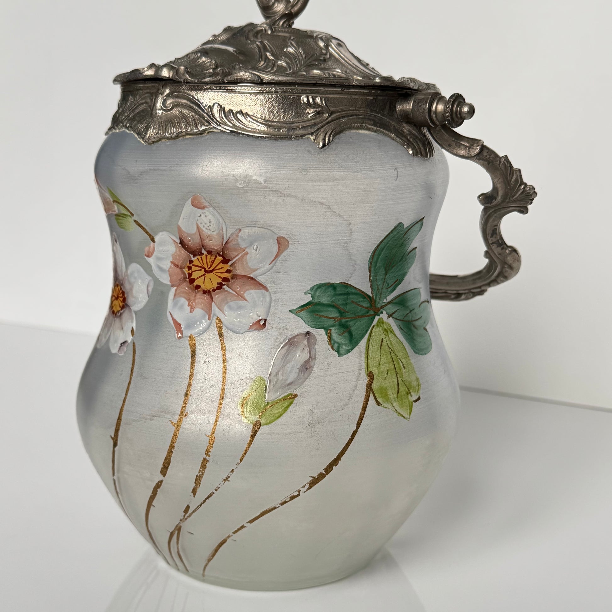 English: Hand-painted glass biscuit jar from the late 19th to early 20th century, featuring floral motifs and Rocaille-style metal mounts from the Art Nouveau period; 日本語: 19世紀後期から20世紀初頭のガラス製ビスケットジャー、アール・ヌーヴォー様式のロカイユ風金属装飾と手描きの花柄入り； Français: Pot à biscuits en verre peint à la main, fin XIXᵉ – début XXᵉ siècle, décor floral et monture en métal de style rocaille de l’époque Art Nouveau.